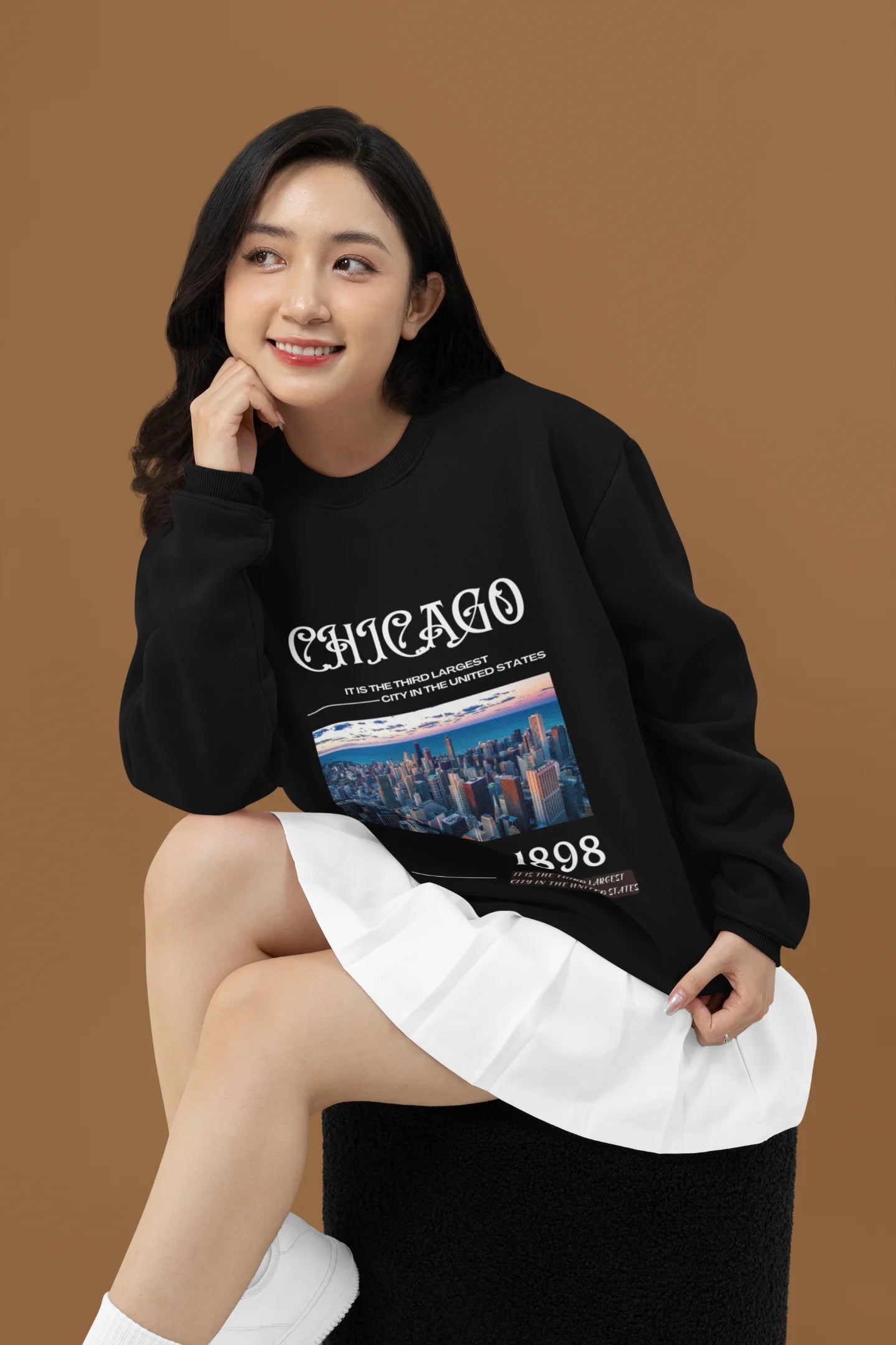 4th front view of female model wearing a black sweatshirt with a Chicago skyline design, offering a relaxed urban aesthetic.