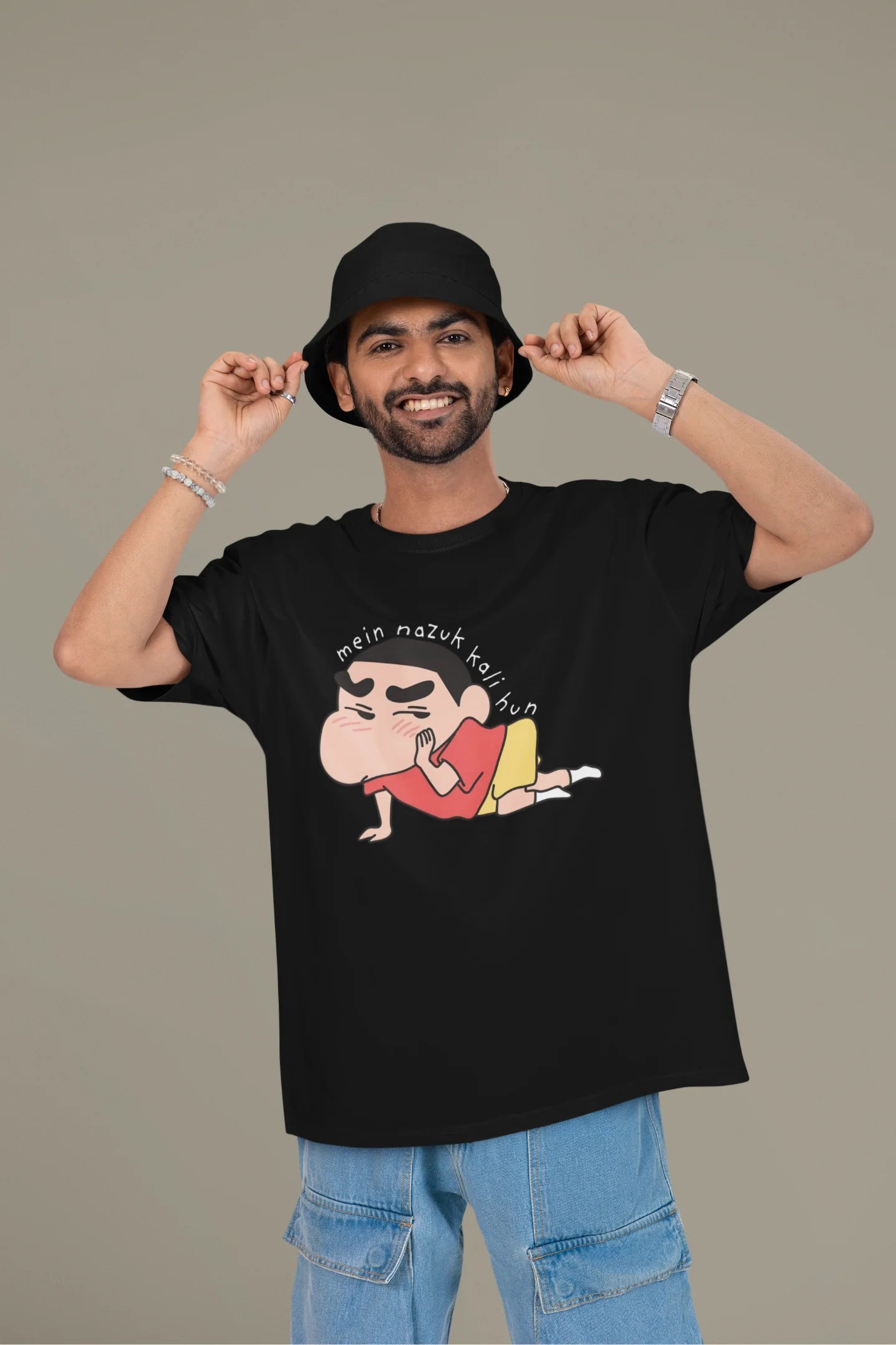 First front view of a male model wearing a black oversized t-shirt featuring Shinchan saying "Mein Nazuk Kali Hun."