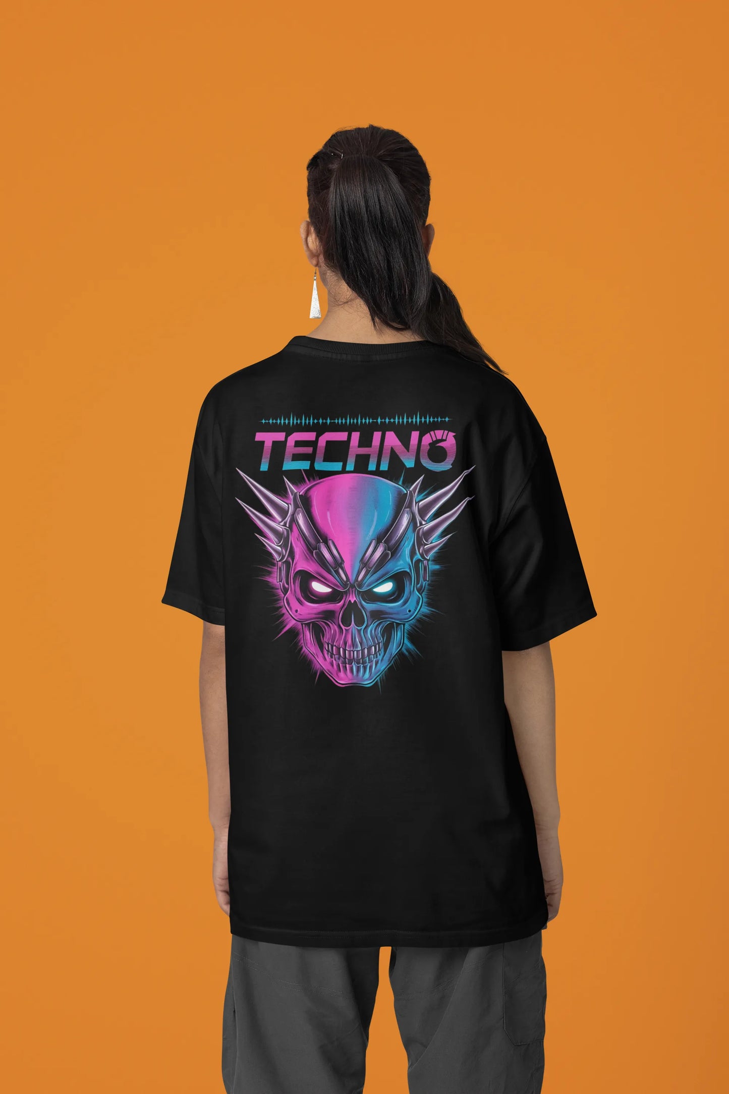 Back view of a female model wearing an black oversized t-shirt with a stylized Techno Skull design, perfect for rave and party vibes.