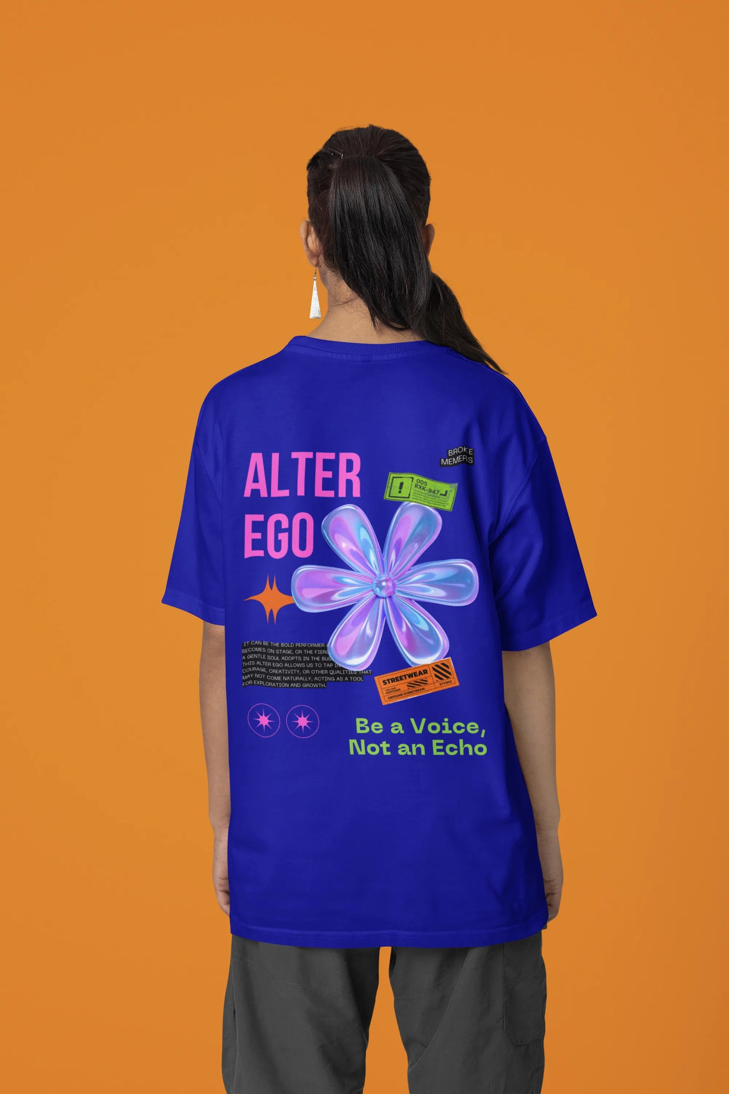 Back view of a female model wearing a royal blue oversized t-shirt with a metal flower design and "Be a Voice, Not an Echo" slogan.