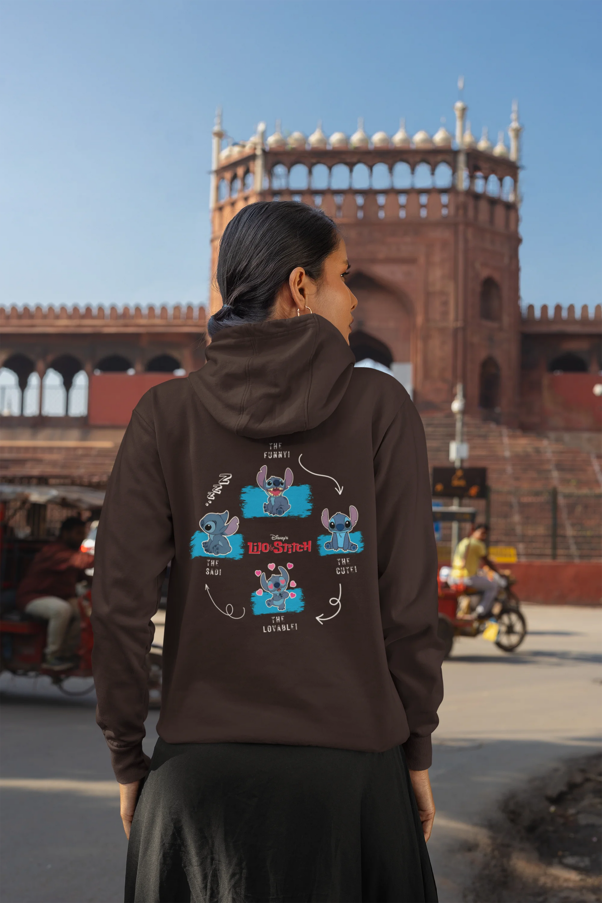 Back view of a female model wearing a chocolate brown hoodie with a collage of Stitch images. The illustration shows Stitch in different poses, making various funny faces and expressions.