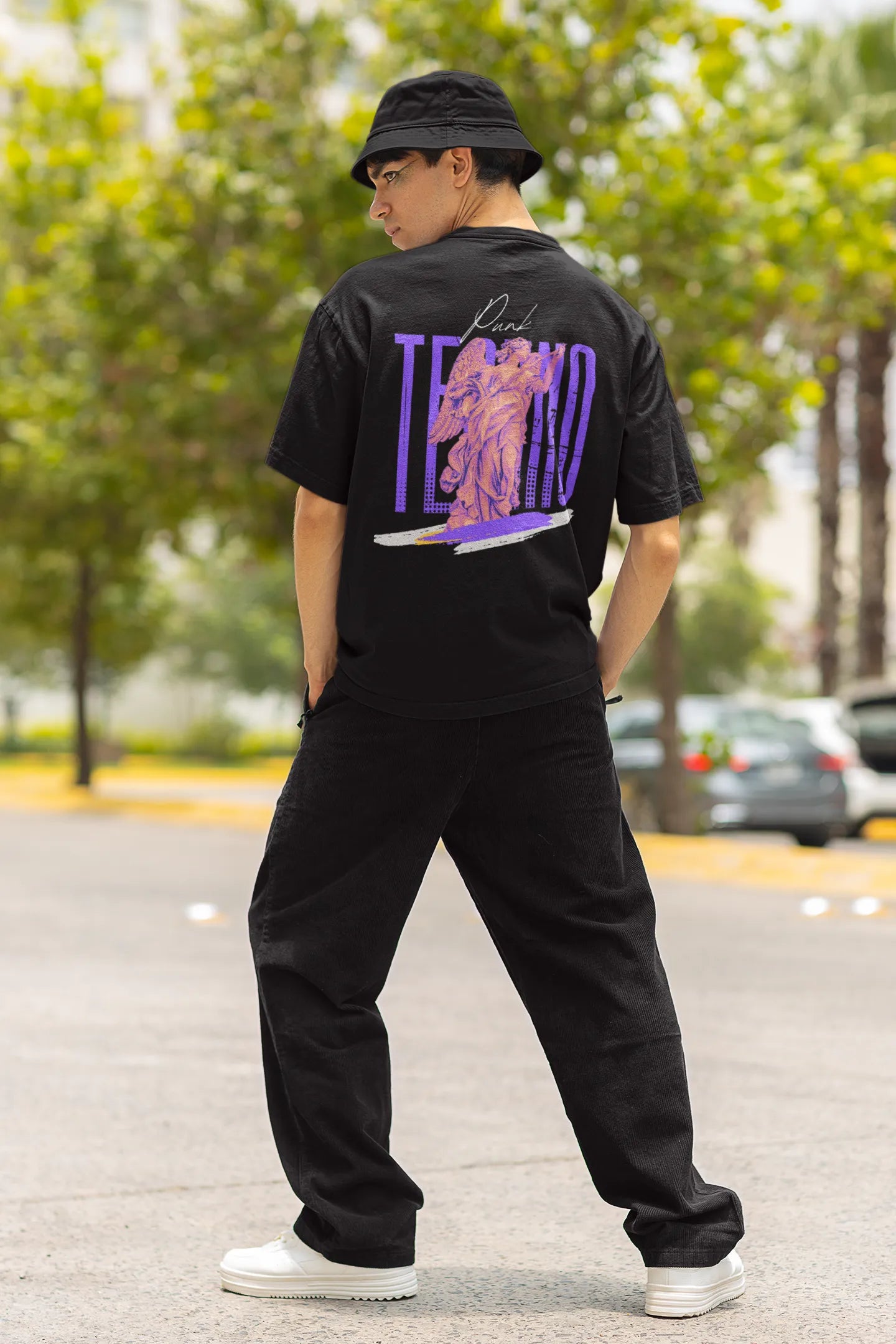 Back view of a male model wearing a black oversized t-shirt with a punk techno angel design, perfect for rave and party wear.