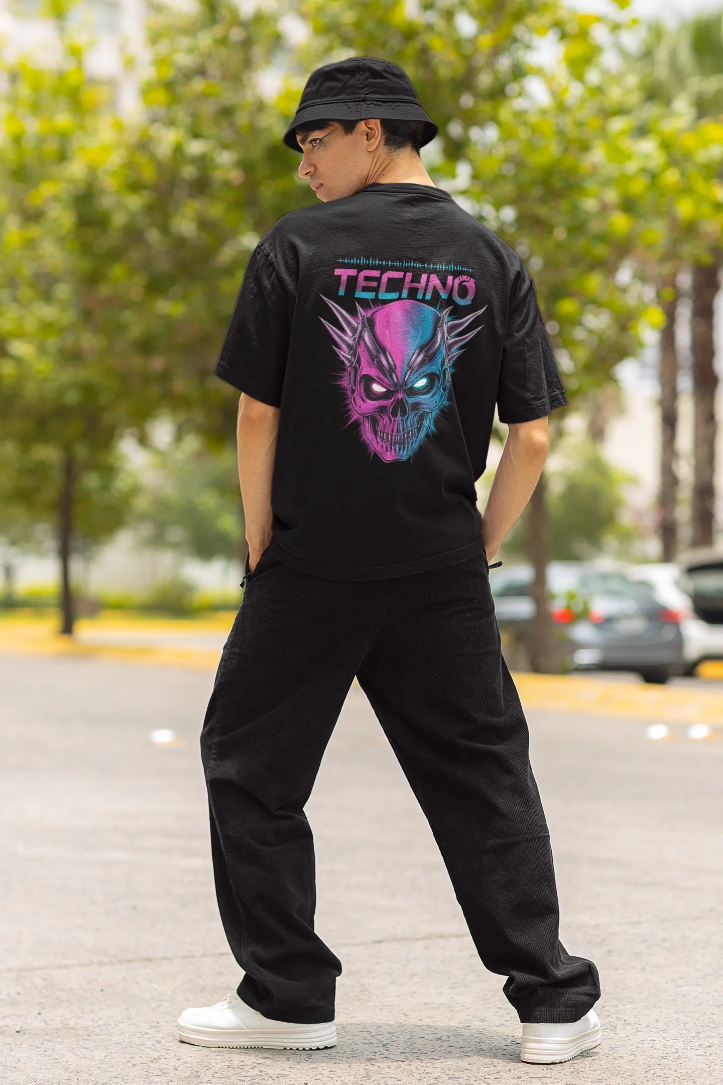 Back view of a male model wearing an black oversized t-shirt with a stylized Techno Skull design, perfect for rave and party vibes.