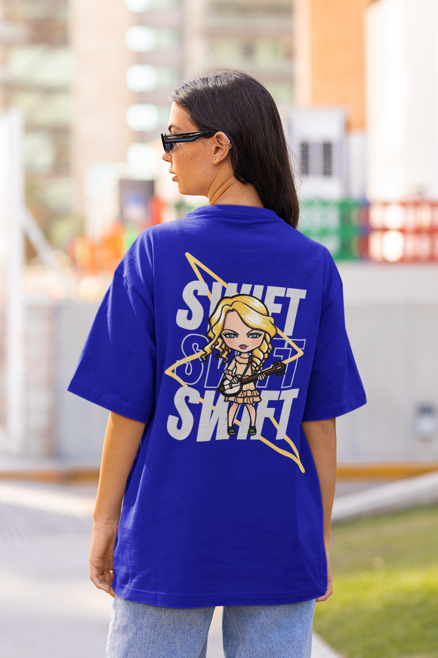 Back view of female model flaunting Taylor Swift-themed blue oversized tee, epitomizing rockstar chic with nods to Taylor's Version and Eras Tour.