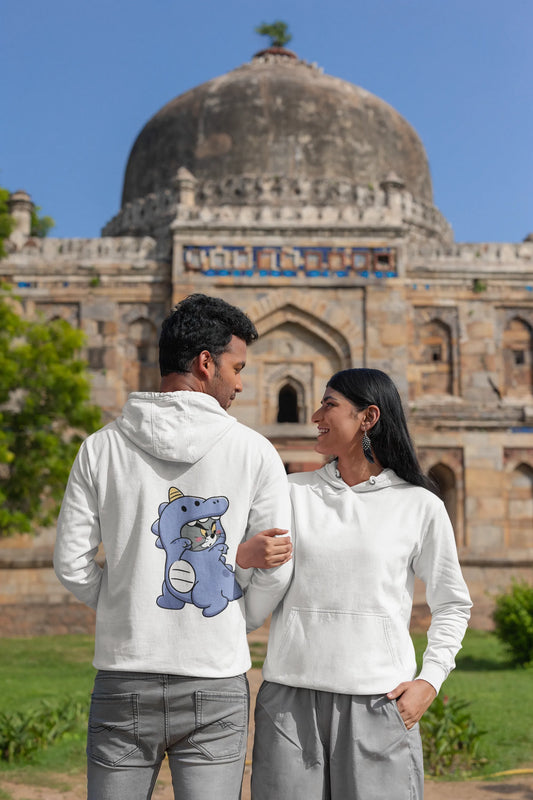 First back and front view of a couple wearing matching cream hoodies, one with Tom the cat and the other with Jerry the mouse, both dressed in dinosaur costumes.