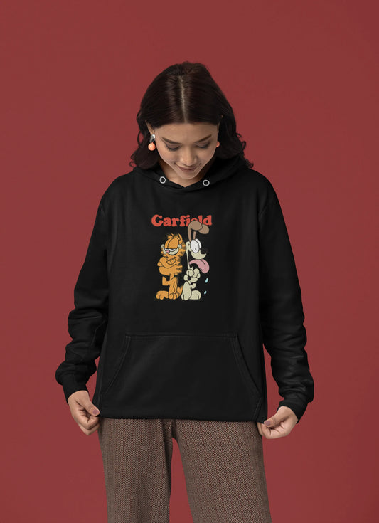 First front view of a female model wearing a black hoodie with a Garfield illustration showing the cat standing back to back with Odie, surrounded by a playful cartoon border.