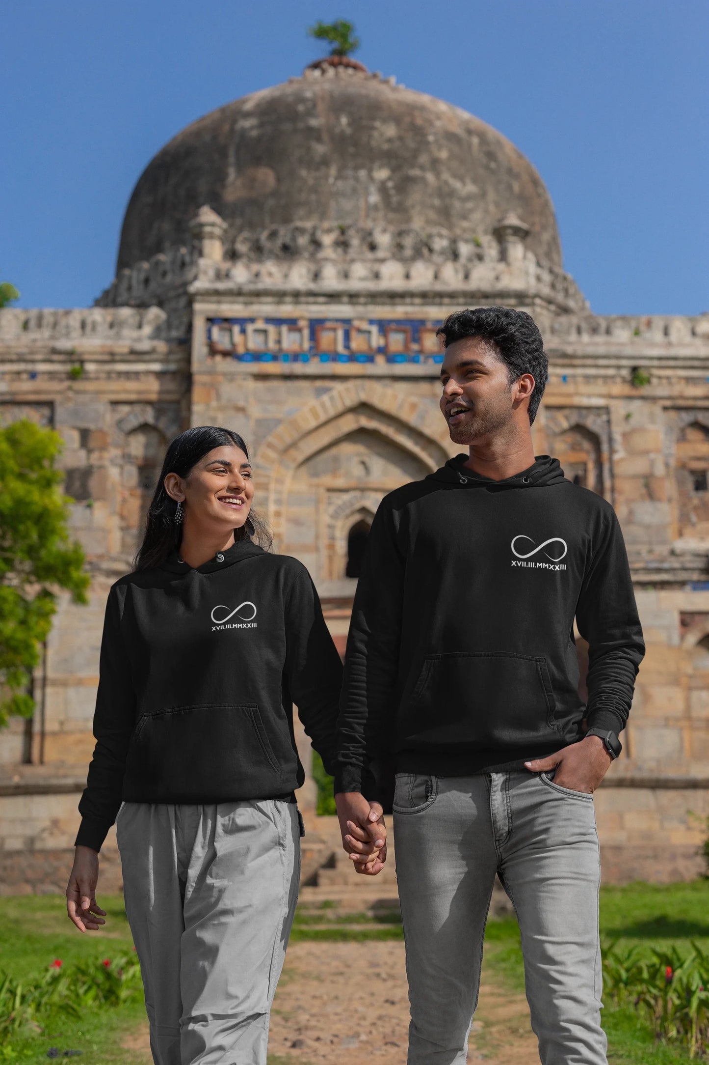 First front view of a couple wearing matching hoodies, each with an infinity loop design and Roman numerals underneath.