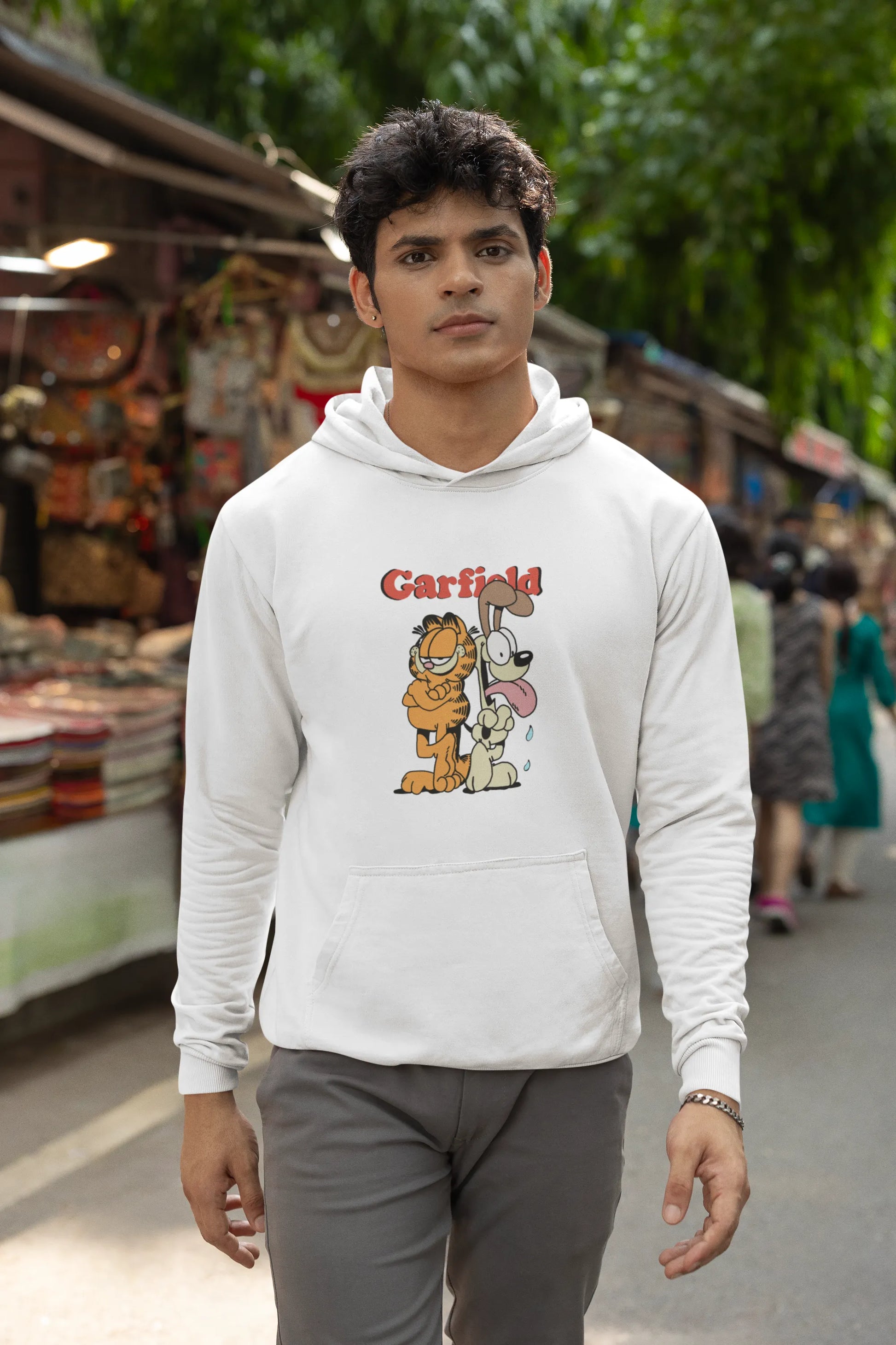 Fourth image of a male model wearing a white hoodie with a Garfield illustration showing the cat standing back to back with Odie, surrounded by a playful cartoon border.