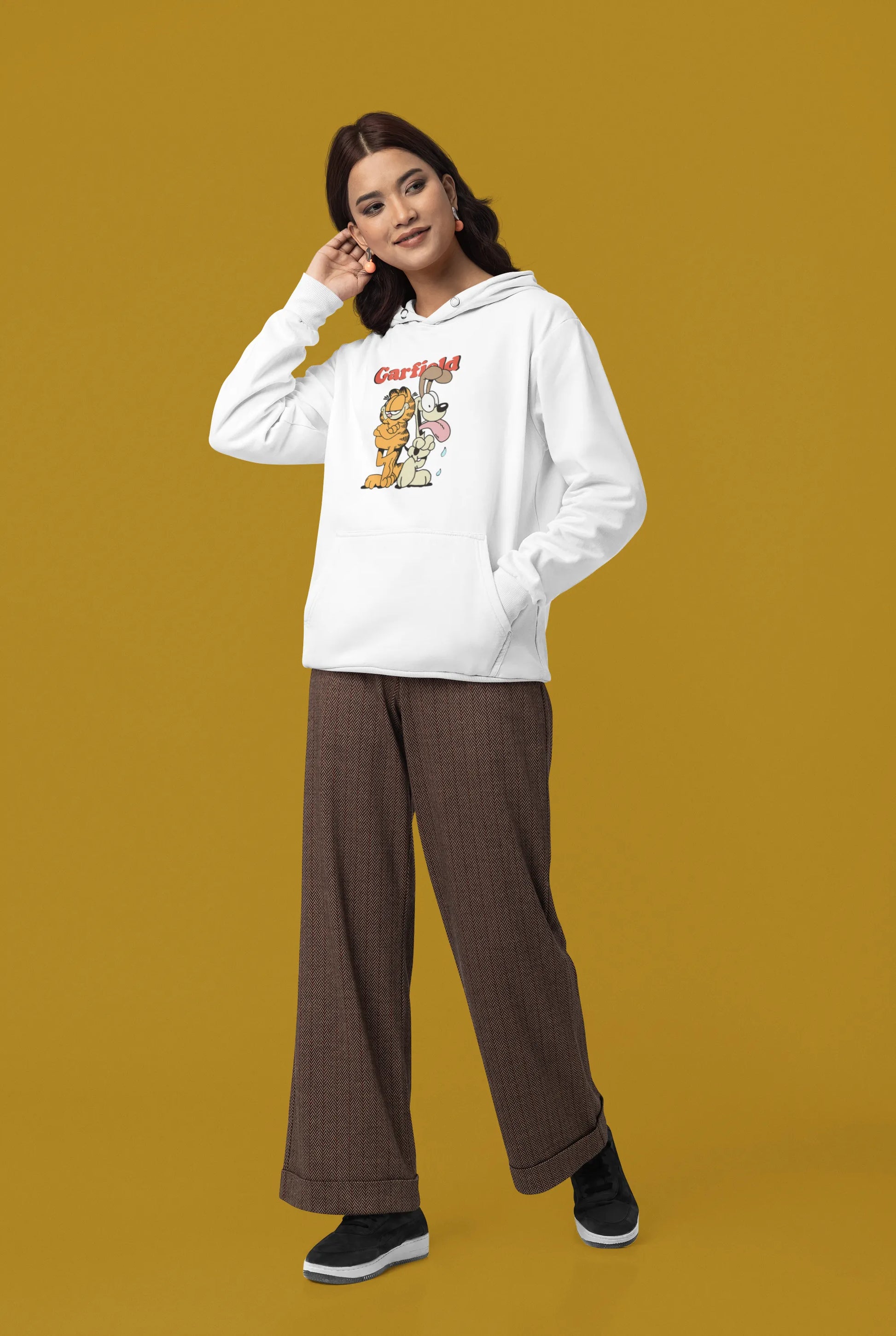 Third image of a female model wearing a white hoodie with a Garfield illustration showing the cat standing back to back with Odie, surrounded by a playful cartoon border.