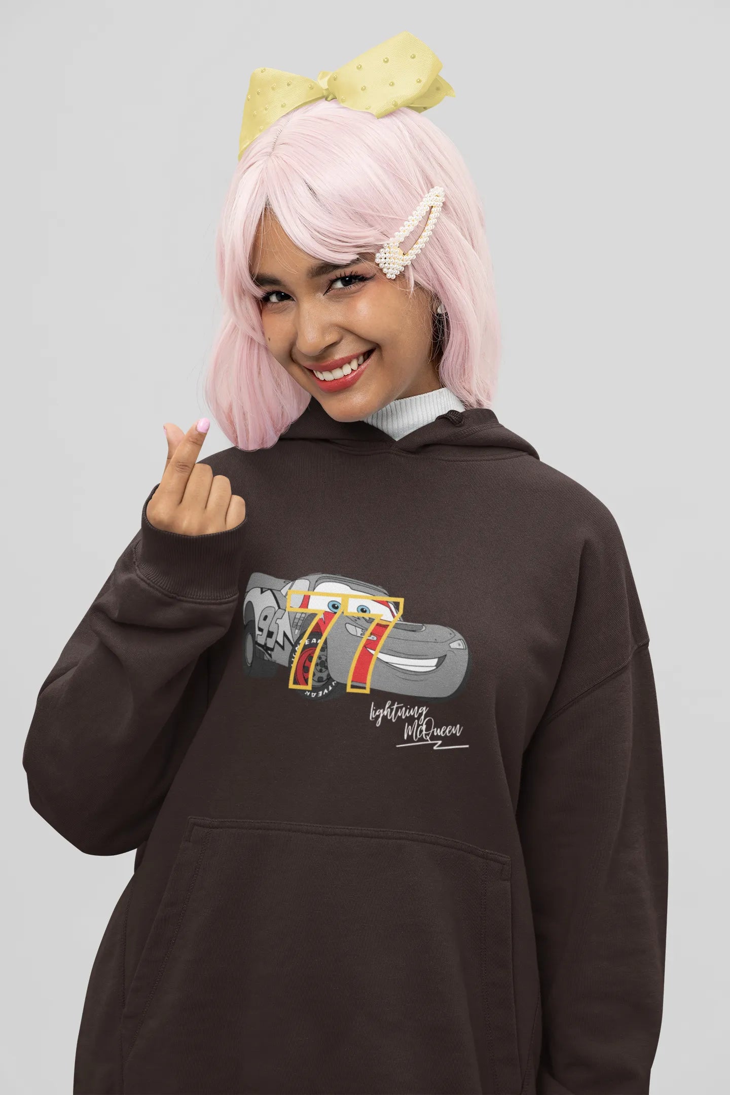 Close up front view of a female model wearing a chocolate brown hoodie with a Disney Cars design featuring Lightning McQueen and the number 77.