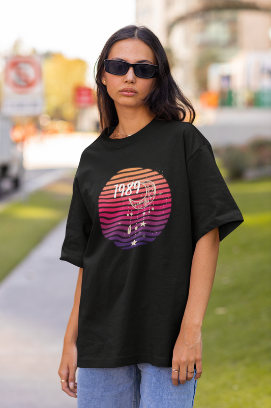 Front view of woman wearing black coloured Oversize T-shirt featuring Taylor Swift 1989 design, Taylor's Version, and Eras Tour Merch