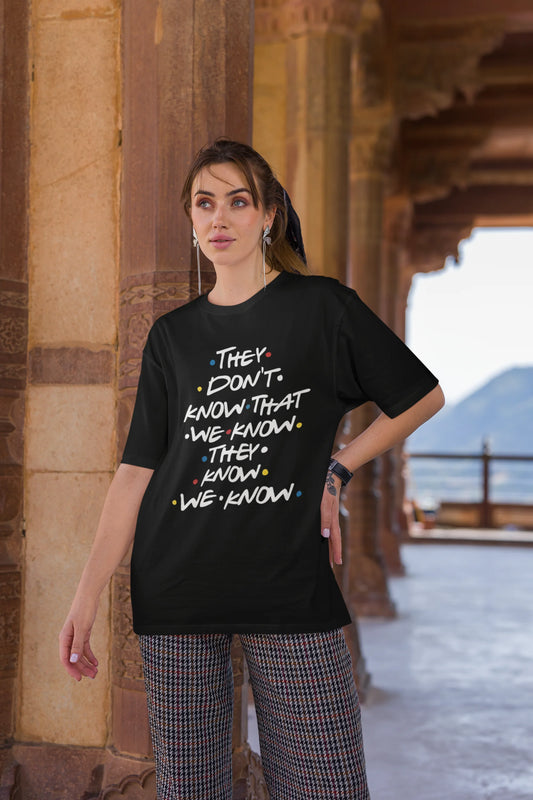Second image of female model wearing black oversized t-shirt with F.R.I.E.N.D.S series inspired designs, embodying Phoebe's unique humor with the quote 'They Know We Know'