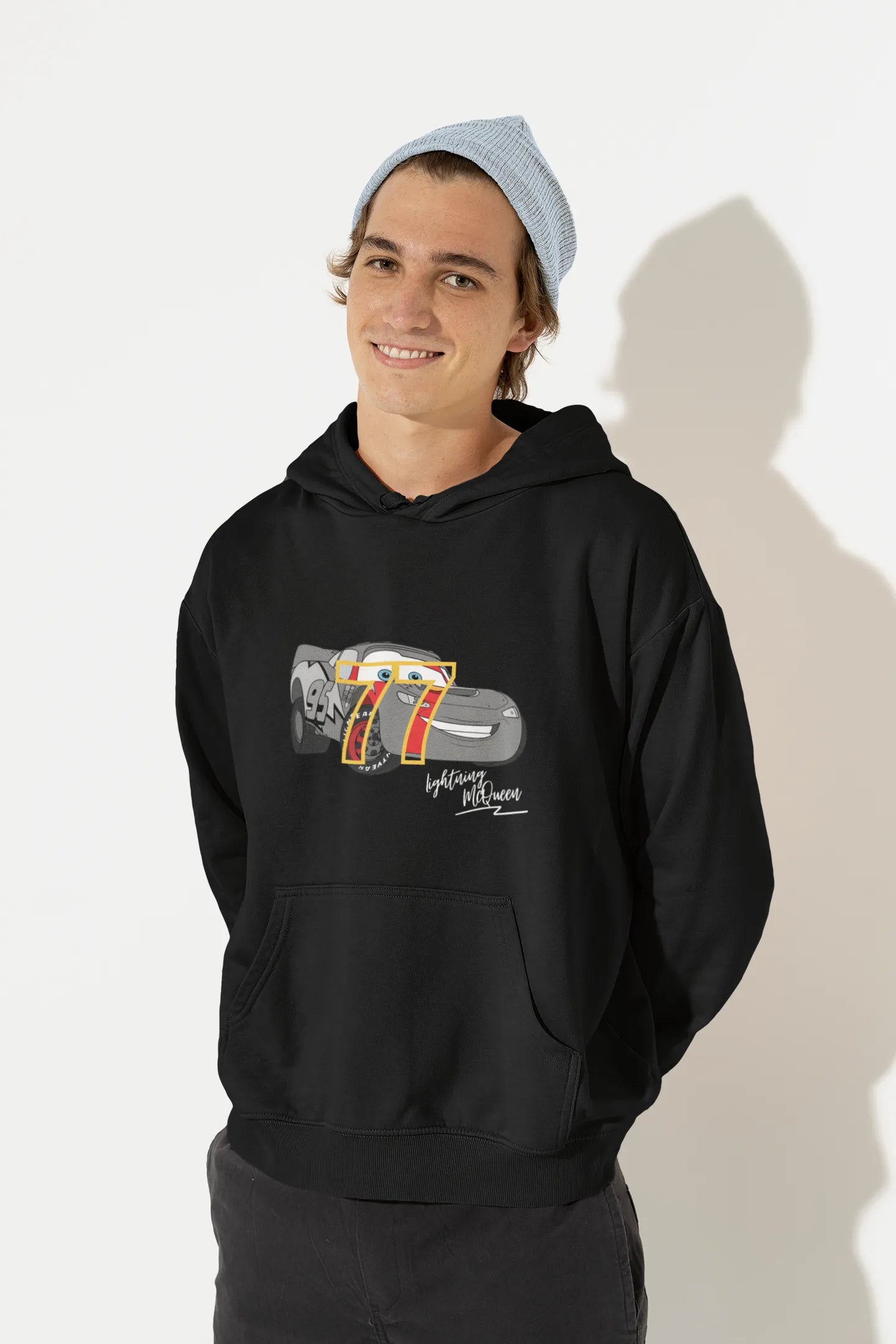 Front view of a male model wearing a black hoodie with a Disney Cars design featuring Lightning McQueen and the number 77.