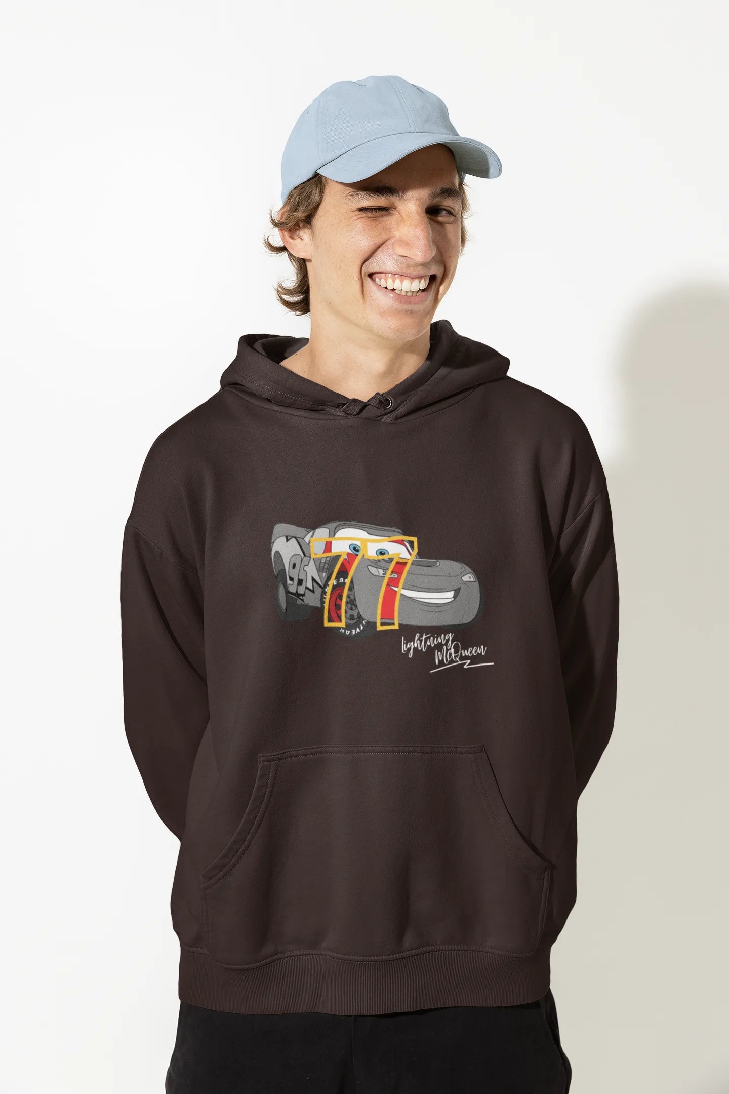 Close up front view of a male model wearing a chocolate brown hoodie with a Disney Cars design featuring Lightning McQueen and the number 77.