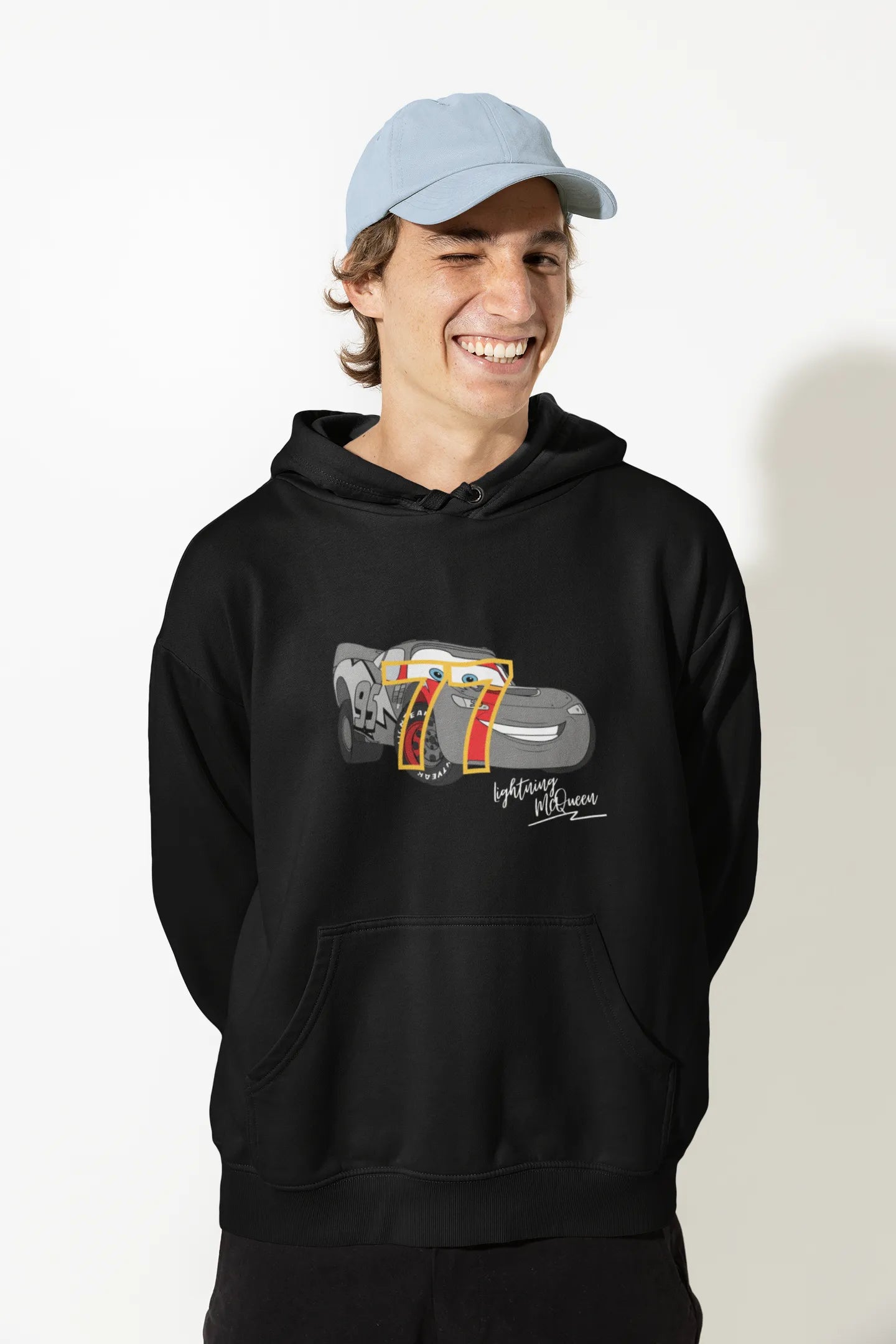 Close up front view of a male model wearing a black hoodie with a Disney Cars design featuring Lightning McQueen and the number 77.