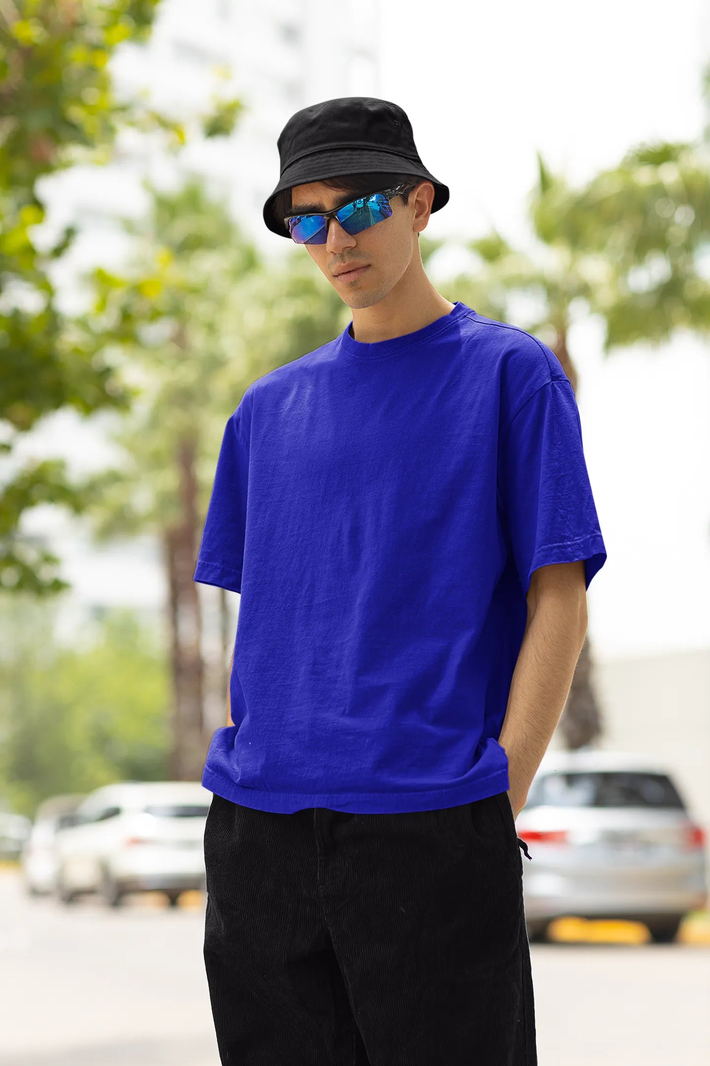 Front view of a male model wearing a royal blue oversized t-shirt with a metal flower design and "Be a Voice, Not an Echo" slogan.
