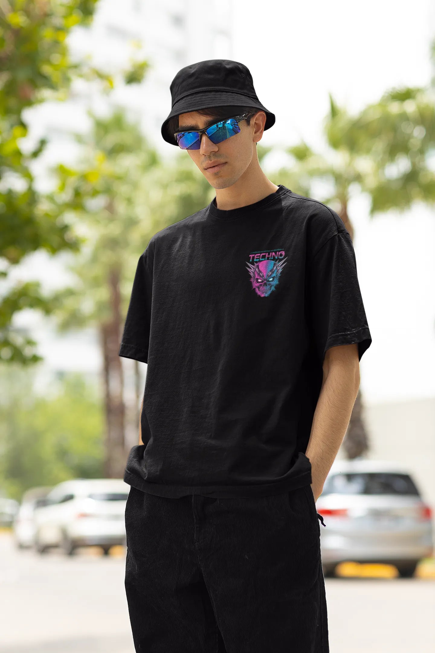 Left side view of a male model wearing an black oversized t-shirt with a stylized Techno Skull design, perfect for rave and party vibes.