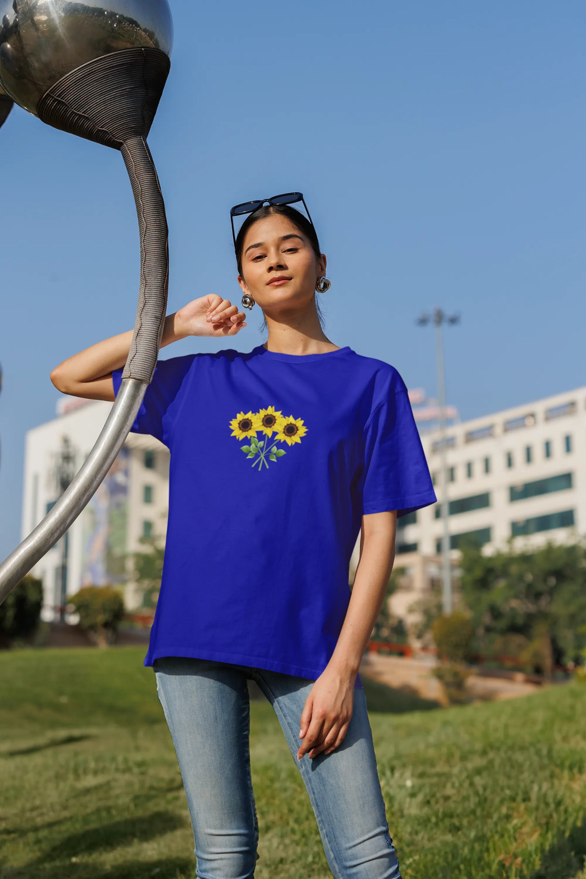 Second front view of a male model wearing a royal blue oversized t-shirt featuring three vibrant sunflowers arranged in a bunch. 
