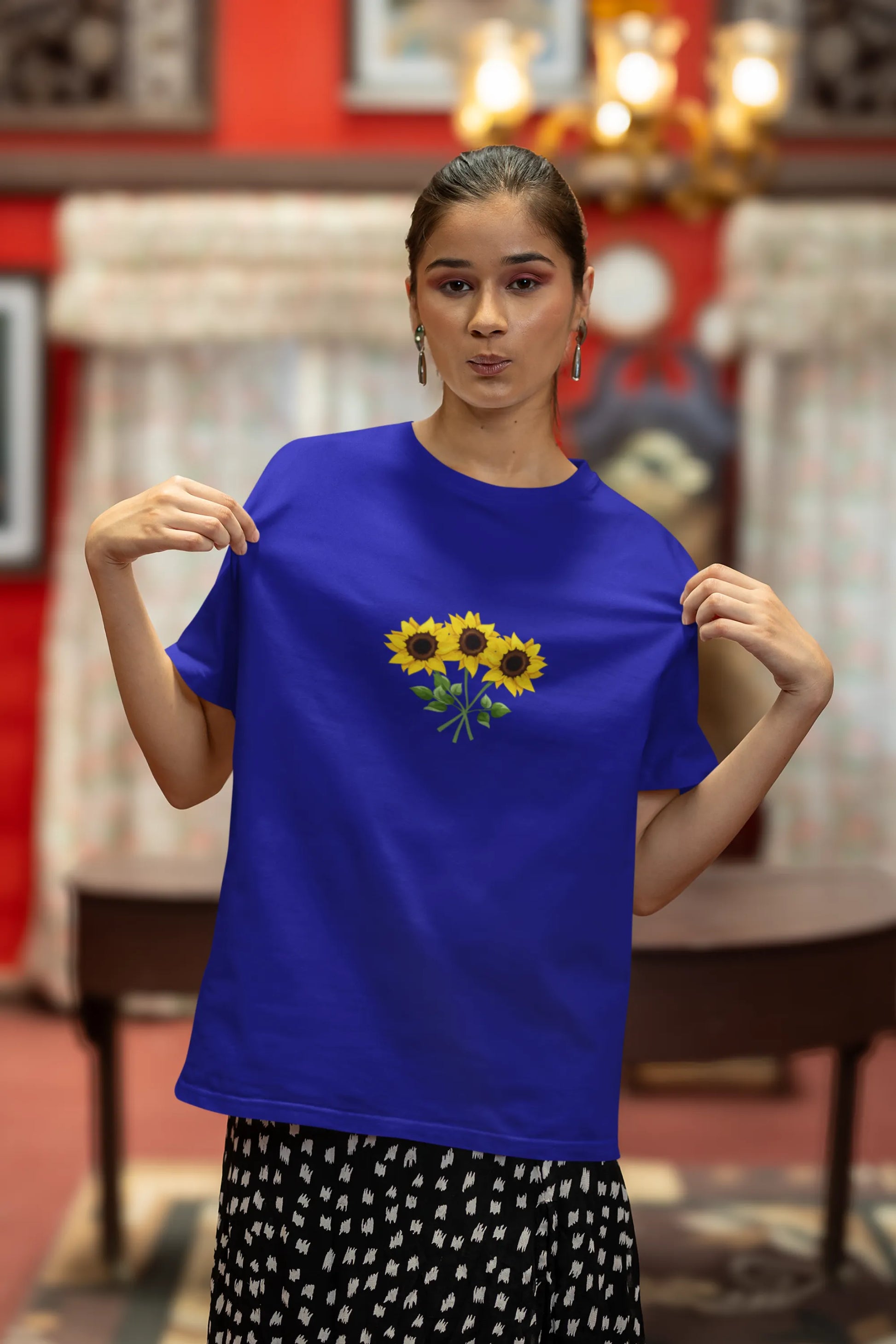 Fourth front view of a male model wearing a royal blue oversized t-shirt featuring three vibrant sunflowers arranged in a bunch. 