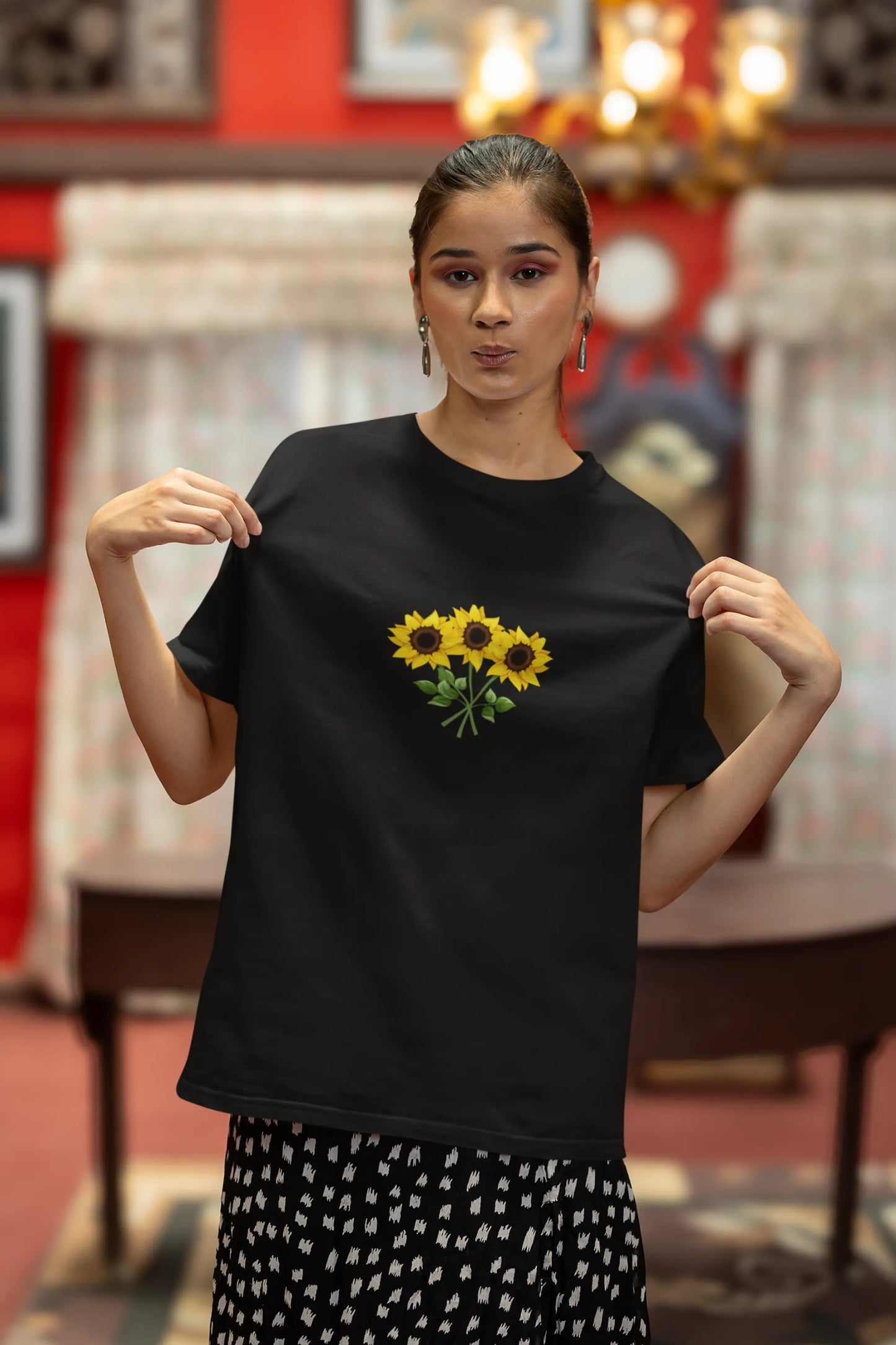 First front view of a female model wearing a black oversized t-shirt featuring three vibrant sunflowers arranged in a bunch. 