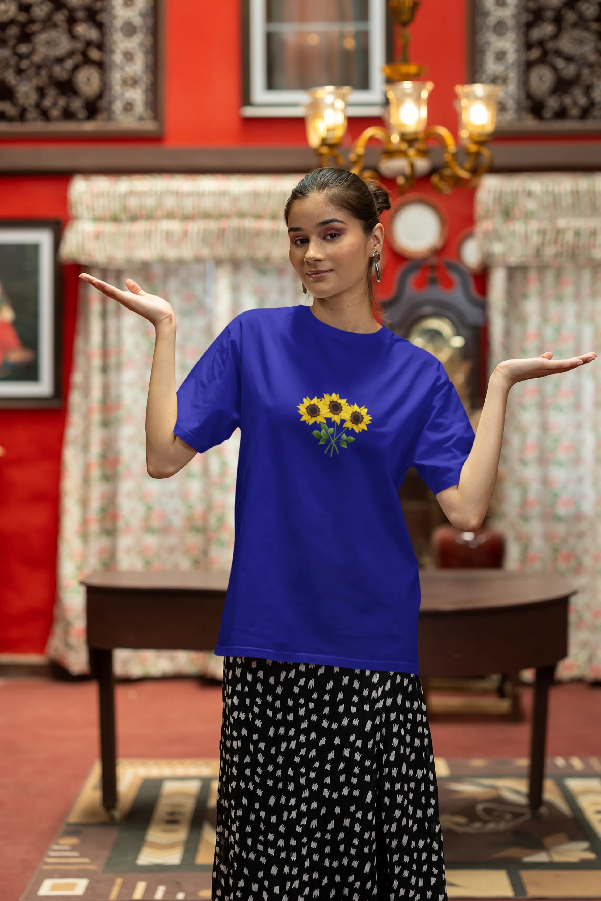 First front view of a female model wearing a royal blue oversized t-shirt featuring three vibrant sunflowers arranged in a bunch. 