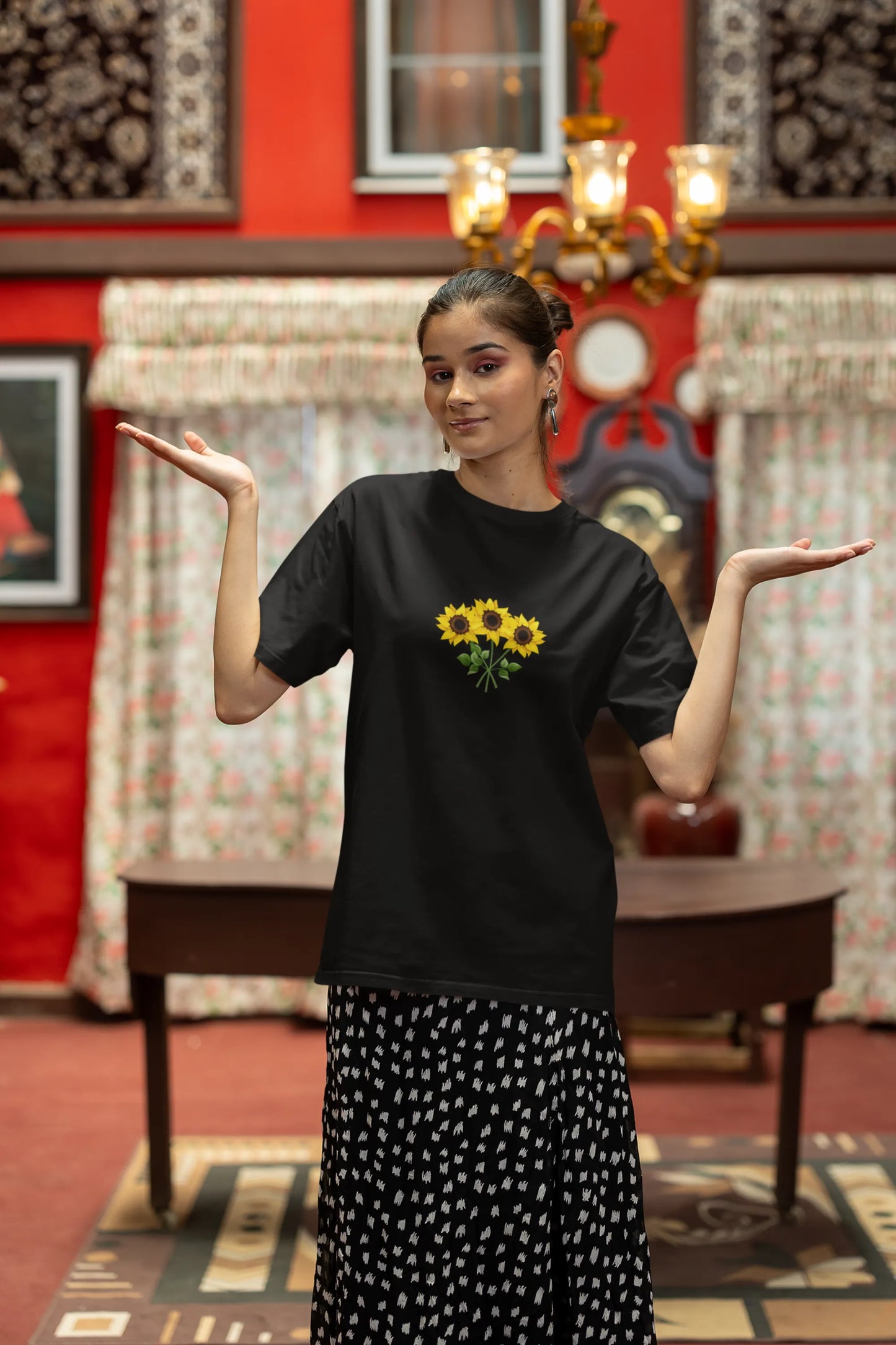 Fourth front view of a female model wearing a black oversized t-shirt featuring three vibrant sunflowers arranged in a bunch. 