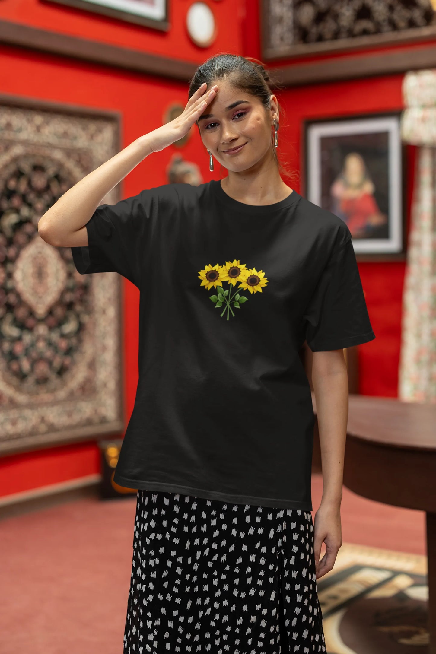 Second front view of a female model wearing a black oversized t-shirt featuring three vibrant sunflowers arranged in a bunch. 