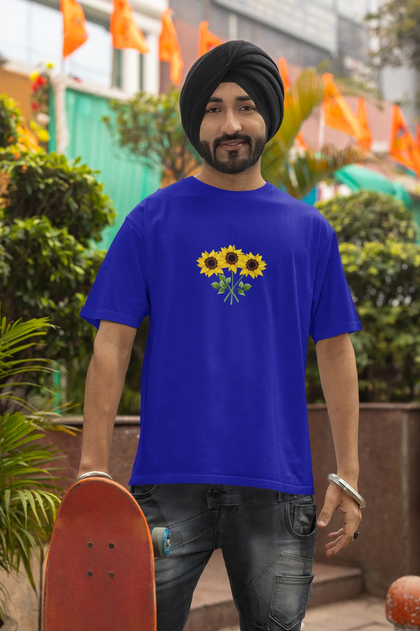 Third front view of a male model wearing a royal blue oversized t-shirt featuring three vibrant sunflowers arranged in a bunch. 