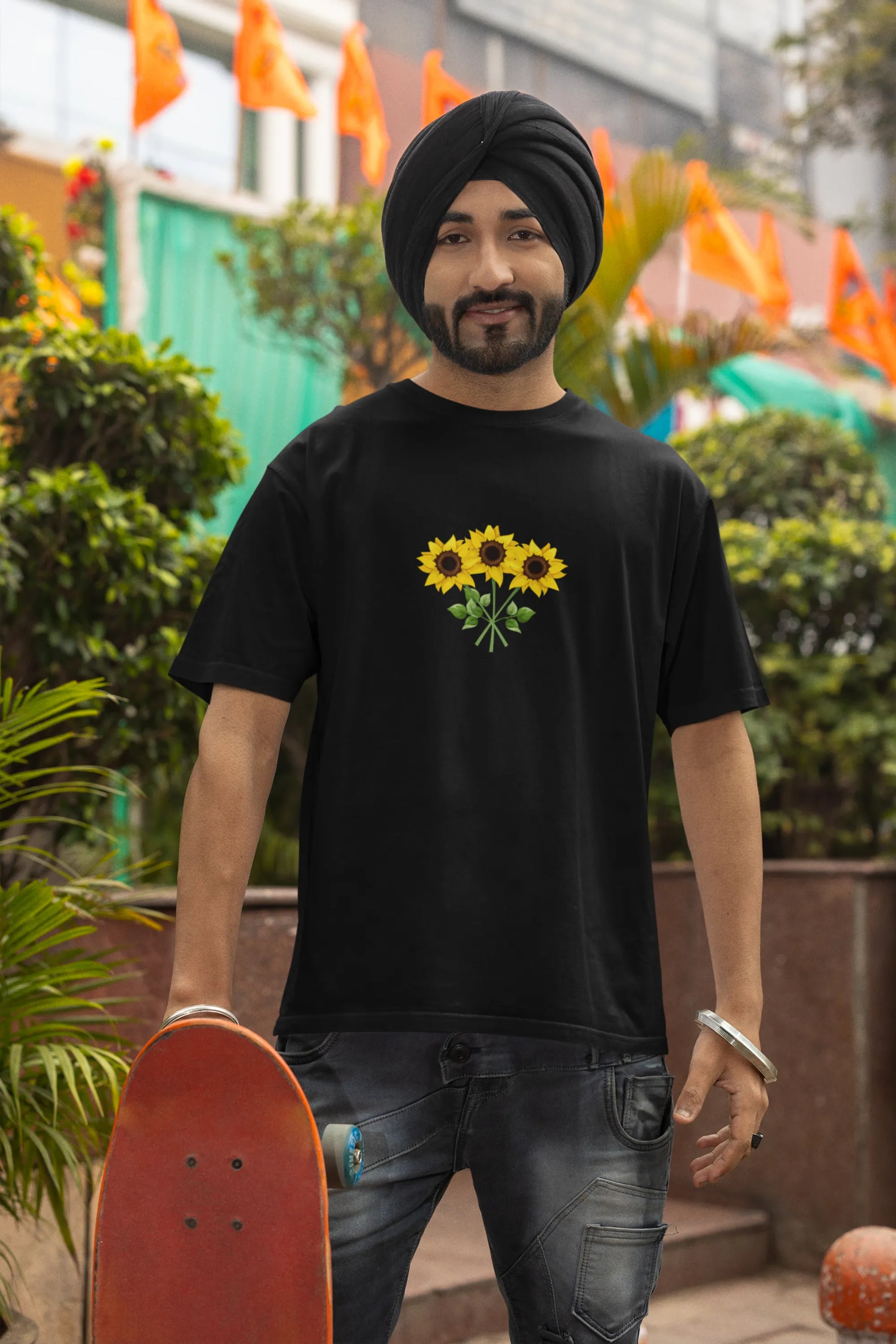 Second front view of a male model wearing a black oversized t-shirt featuring three vibrant sunflowers arranged in a bunch. 