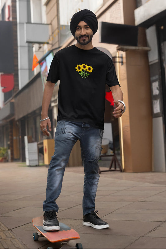 First front view of a male model wearing a black oversized t-shirt featuring three vibrant sunflowers arranged in a bunch. 
