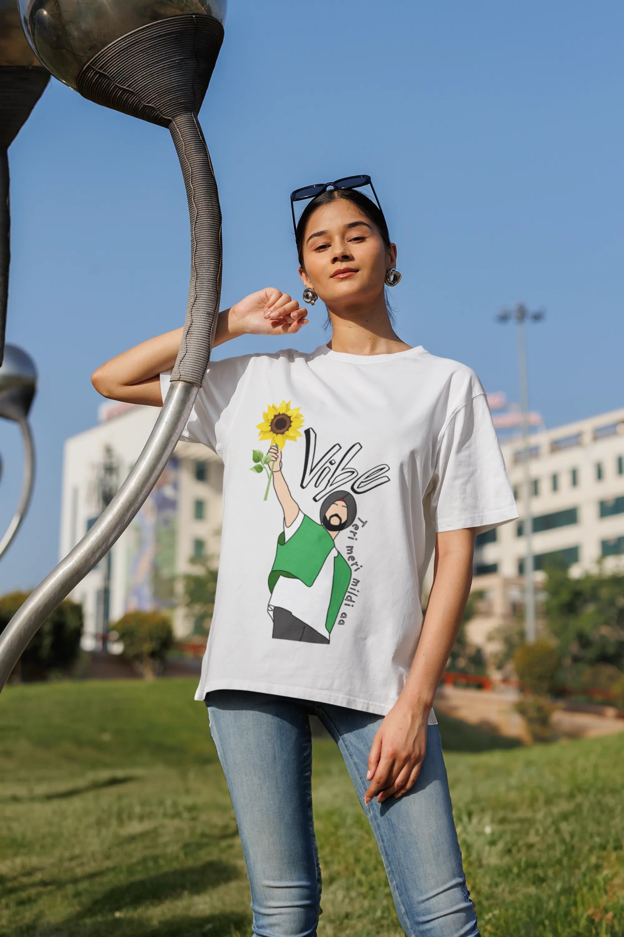 Fourth front view of female model wearing a off-white oversized t shirt with a design of Diljit Dosanjh holding a sunflower, with the text "Vibe Teri Meri".