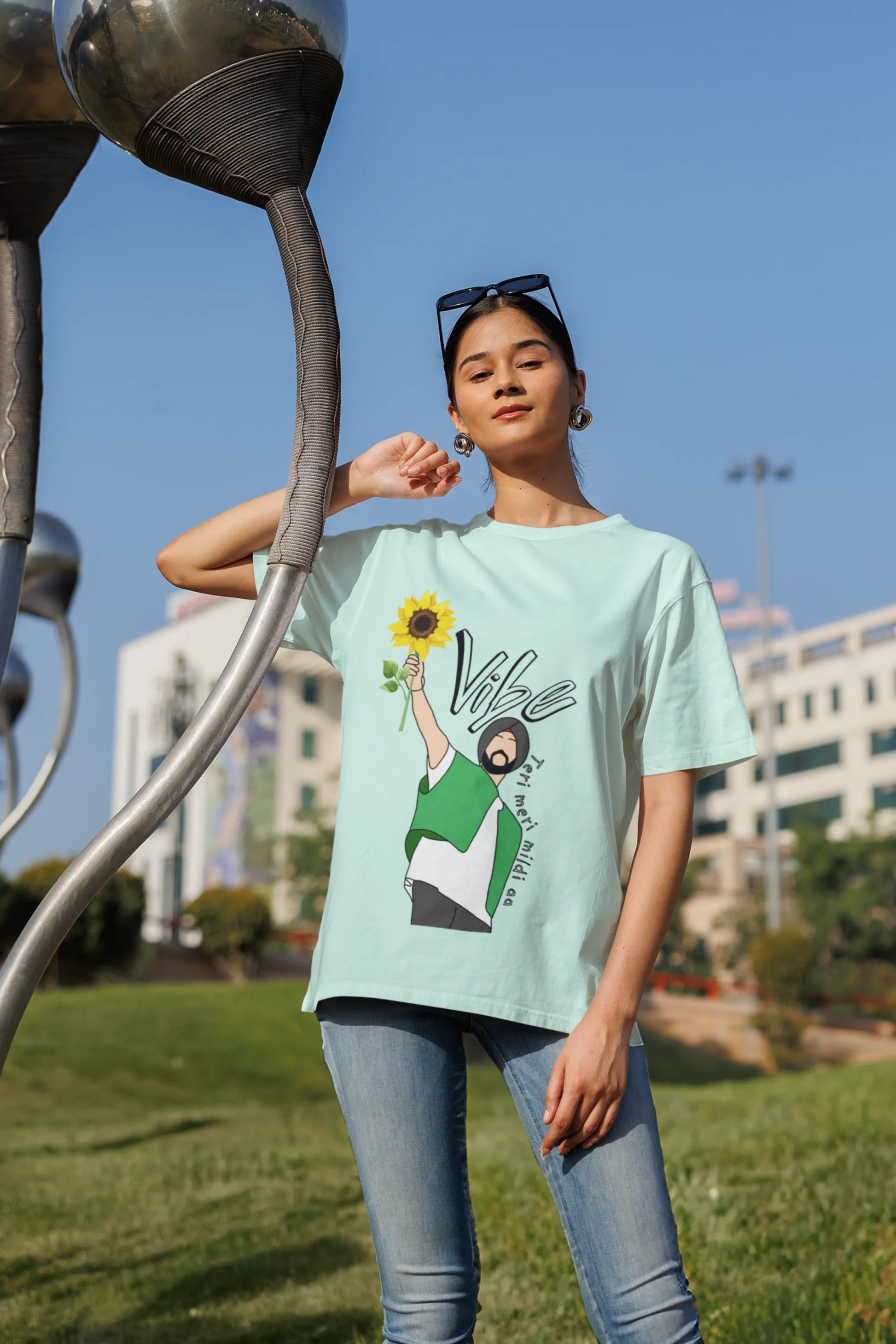 Fourth front view of female model wearing a mint green oversized t shirt with a design of Diljit Dosanjh holding a sunflower, with the text "Vibe Teri Meri".