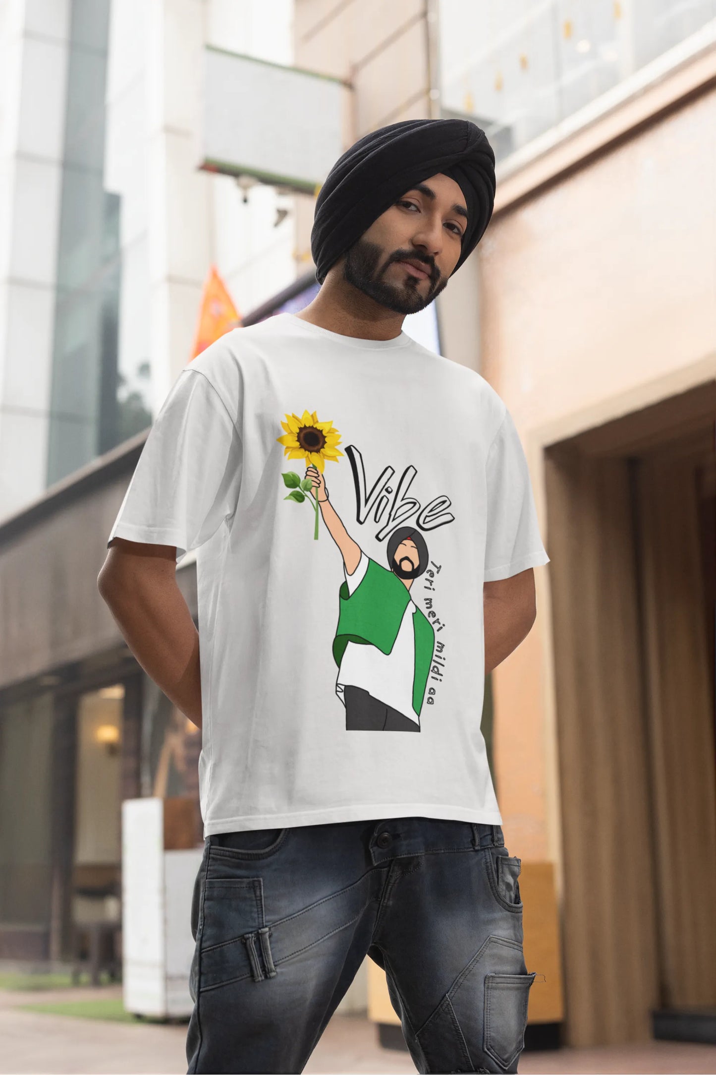 Third front view of male model wearing a off-white oversized t shirt with a design of Diljit Dosanjh holding a sunflower, with the text "Vibe Teri Meri".