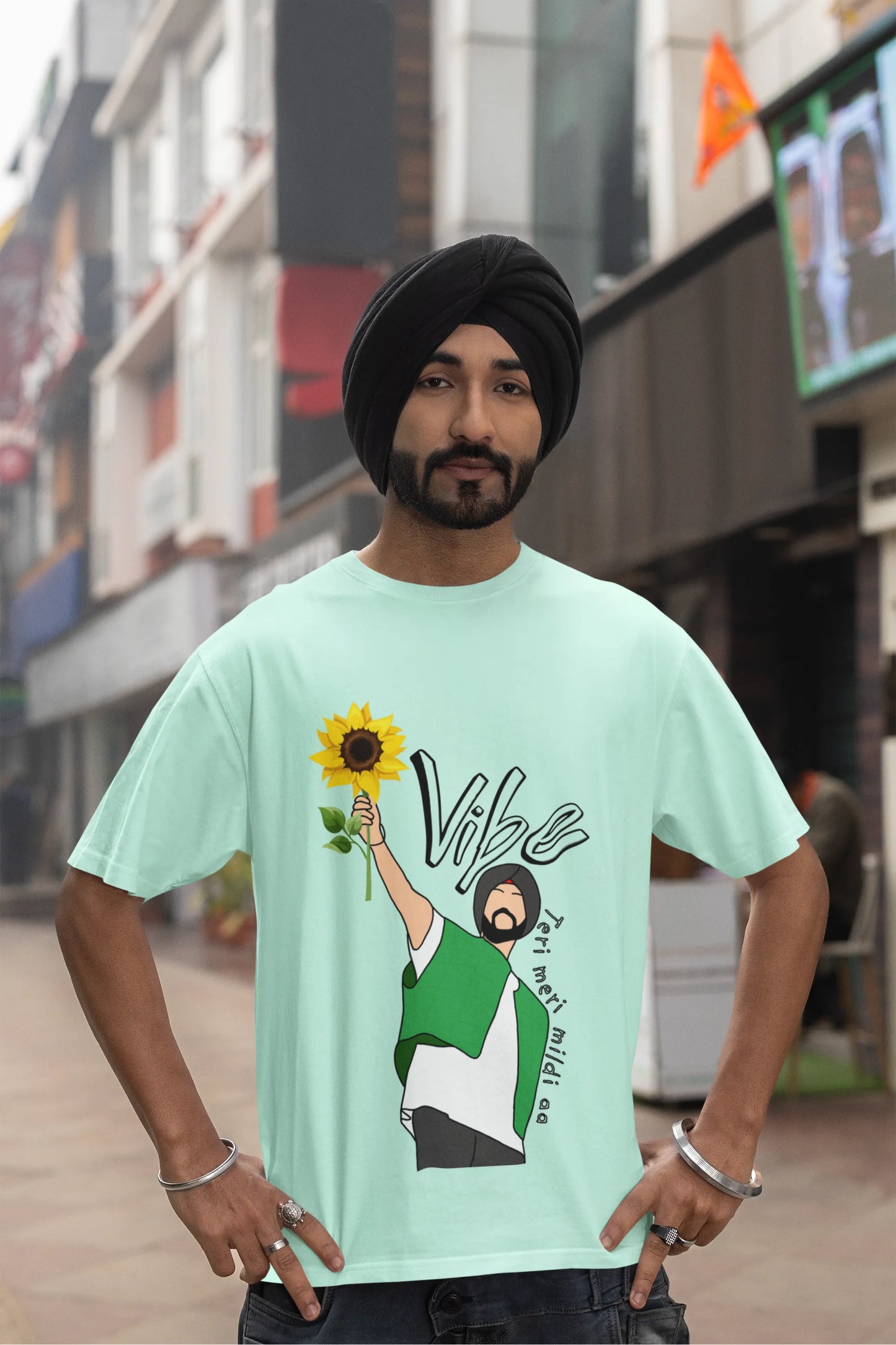 Fourth front view of male model wearing a mint green oversized t shirt with a design of Diljit Dosanjh holding a sunflower, with the text "Vibe Teri Meri".