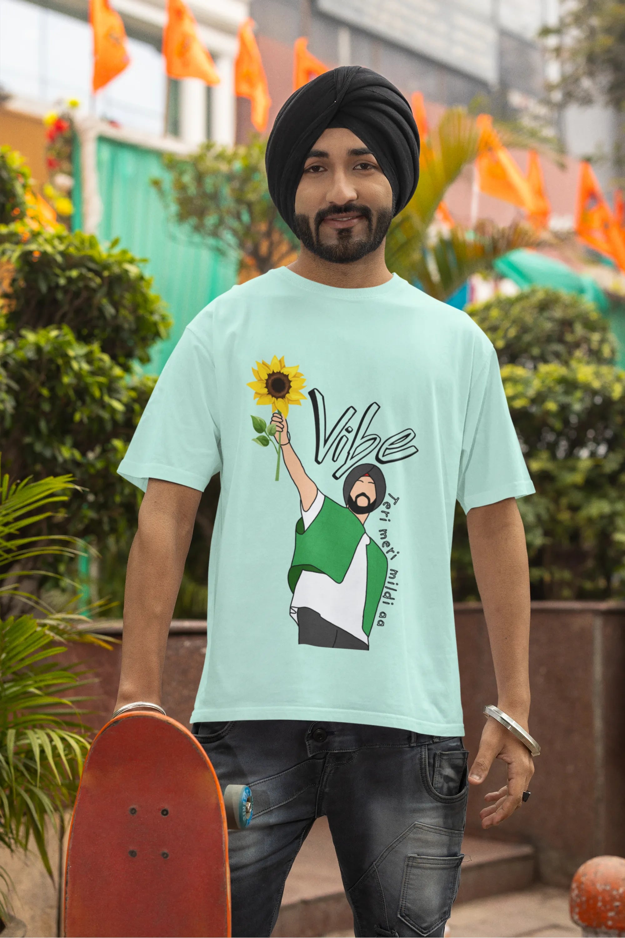 Third front view of male model wearing a mint green oversized t shirt with a design of Diljit Dosanjh holding a sunflower, with the text "Vibe Teri Meri".