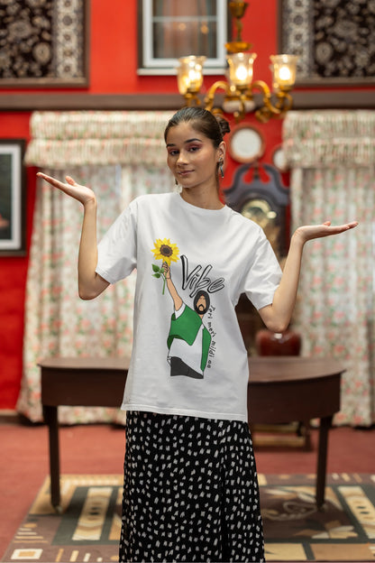 Third front view of female model wearing a off-white oversized t shirt with a design of Diljit Dosanjh holding a sunflower, with the text "Vibe Teri Meri".