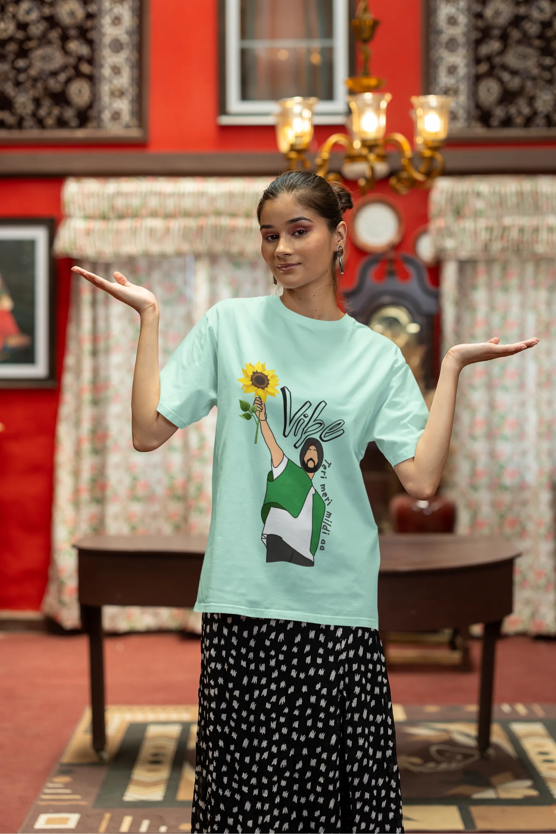 Third front view of female model wearing a mint green oversized t shirt with a design of Diljit Dosanjh holding a sunflower, with the text "Vibe Teri Meri".
