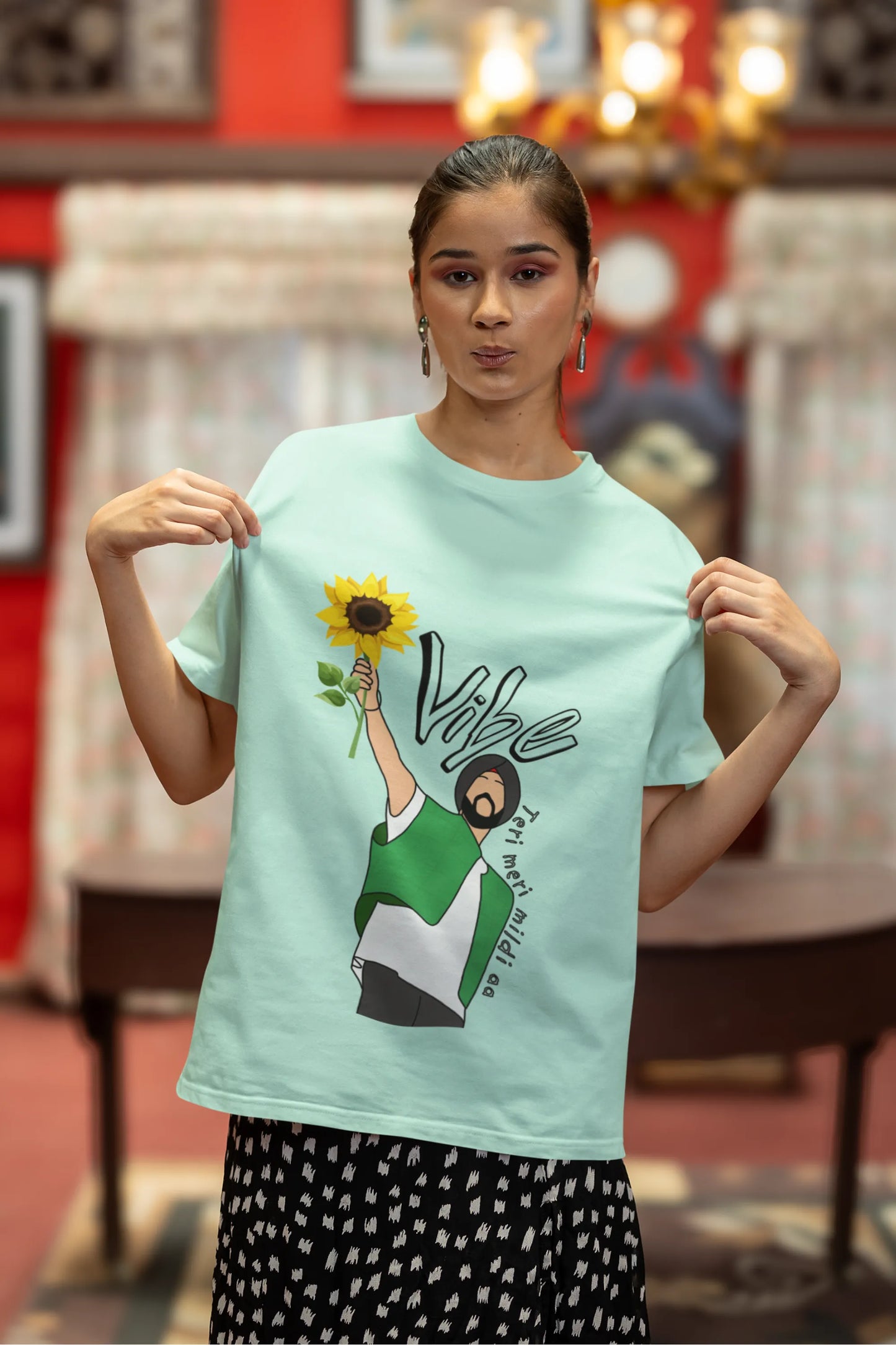 Second front view of female model wearing a mint green oversized t shirt with a design of Diljit Dosanjh holding a sunflower, with the text "Vibe Teri Meri".