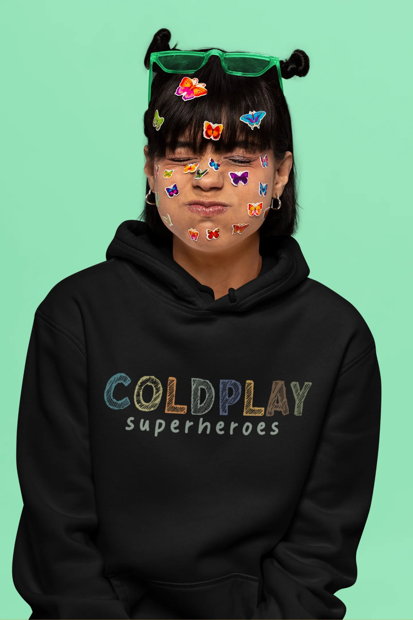 5th front view of a female model wearing an black hoodie with a design inspired by the "Something Just Like This" music video, featuring the word "Superheroes".