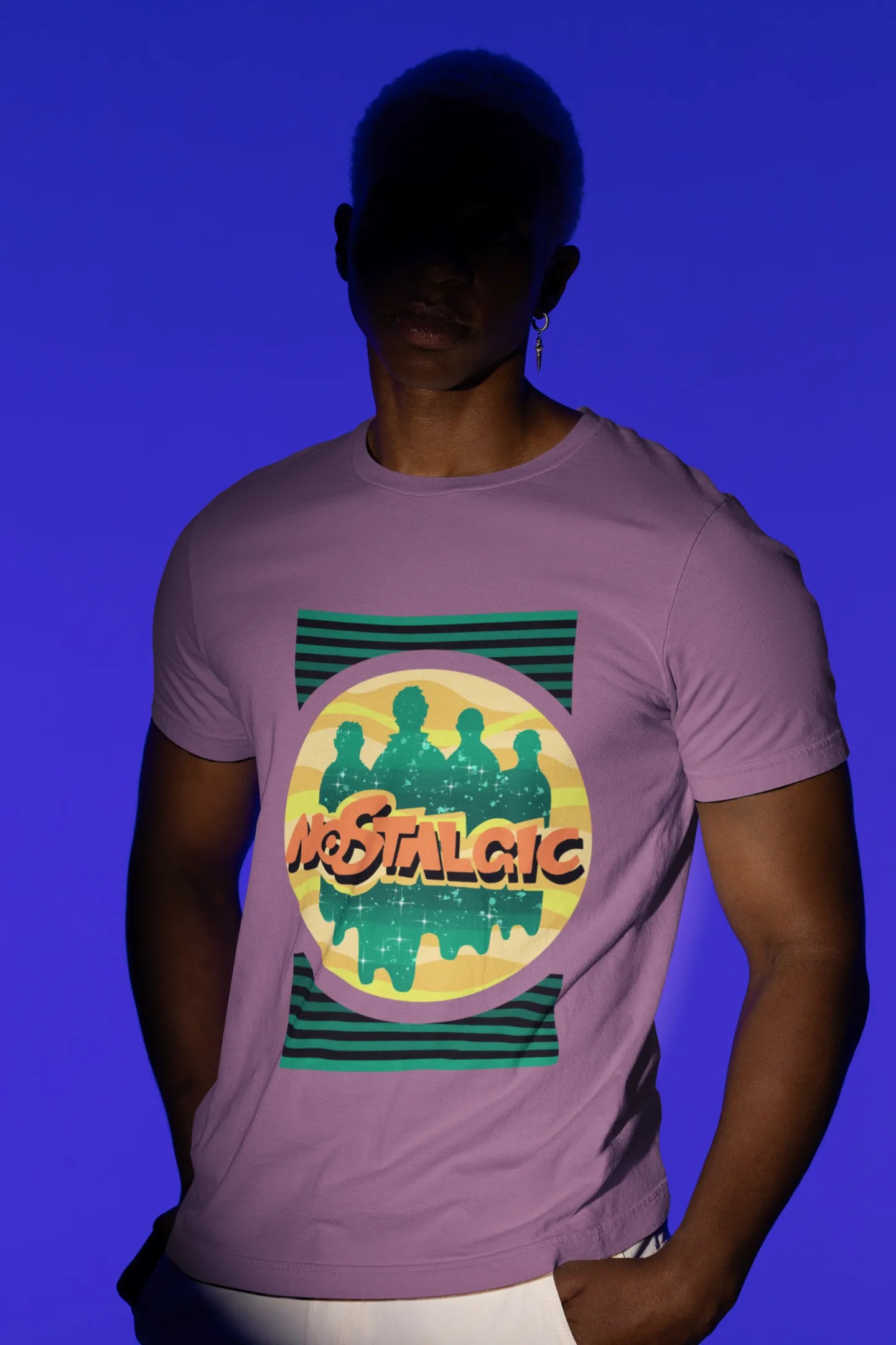 Second view of a male model wearing an oversized dirty purple t-shirt with a shadow silhouette of the Coldplay band members and the word "Nostalgic" printed on it.