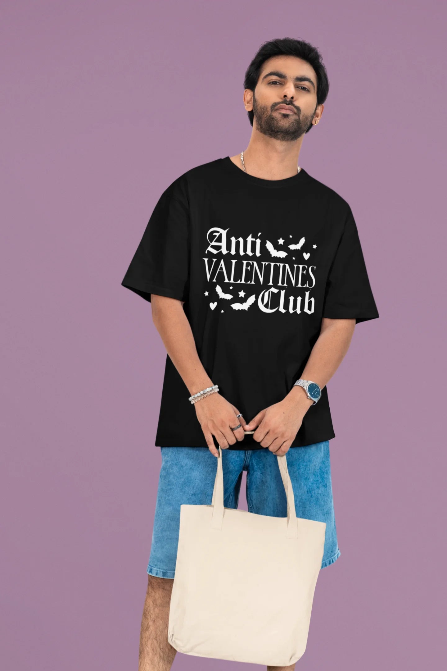 First front view of a male model wearing a black oversized t-shirt with the text "Anti-Valentine's Club" printed on it.