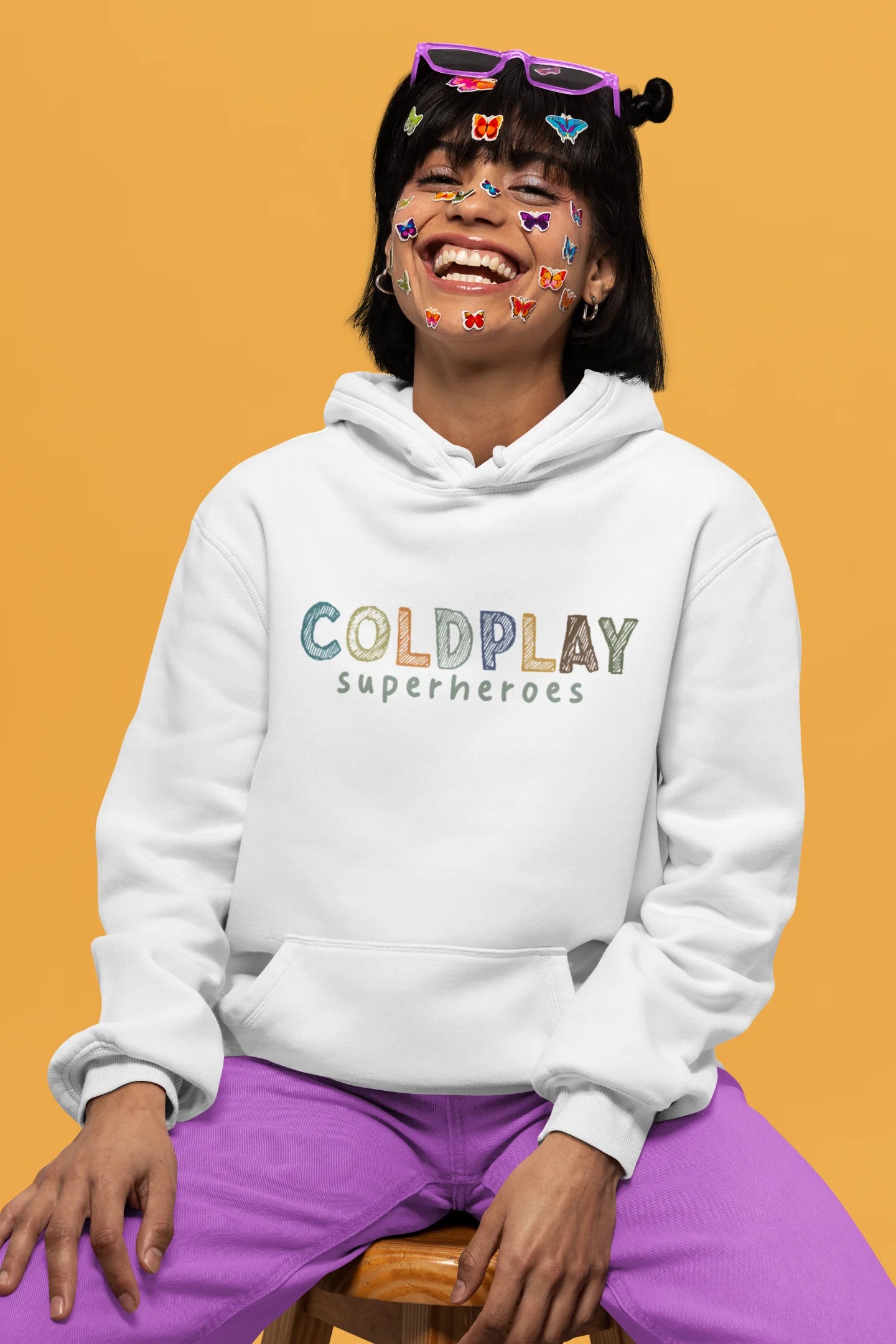 1st front view of a female model wearing an off-white hoodie with a design inspired by the "Something Just Like This" music video, featuring the word "Superheroes".