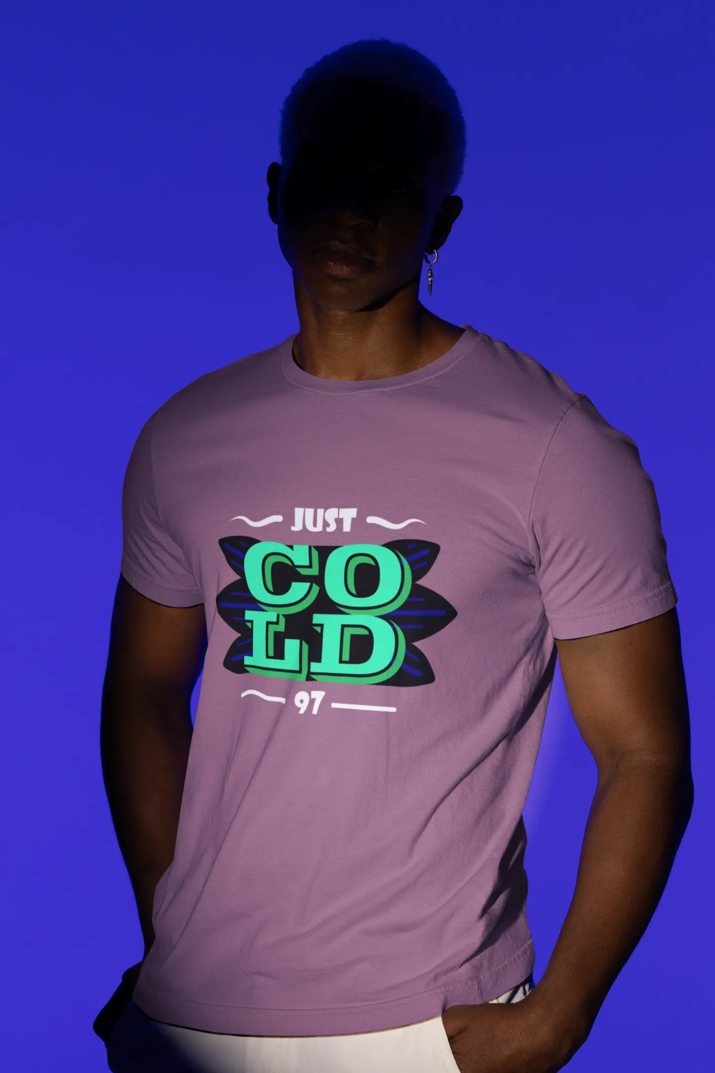 First front view of a male model wearing an dirty purple oversized t-shirt with the text "Just Cold" printed on it.