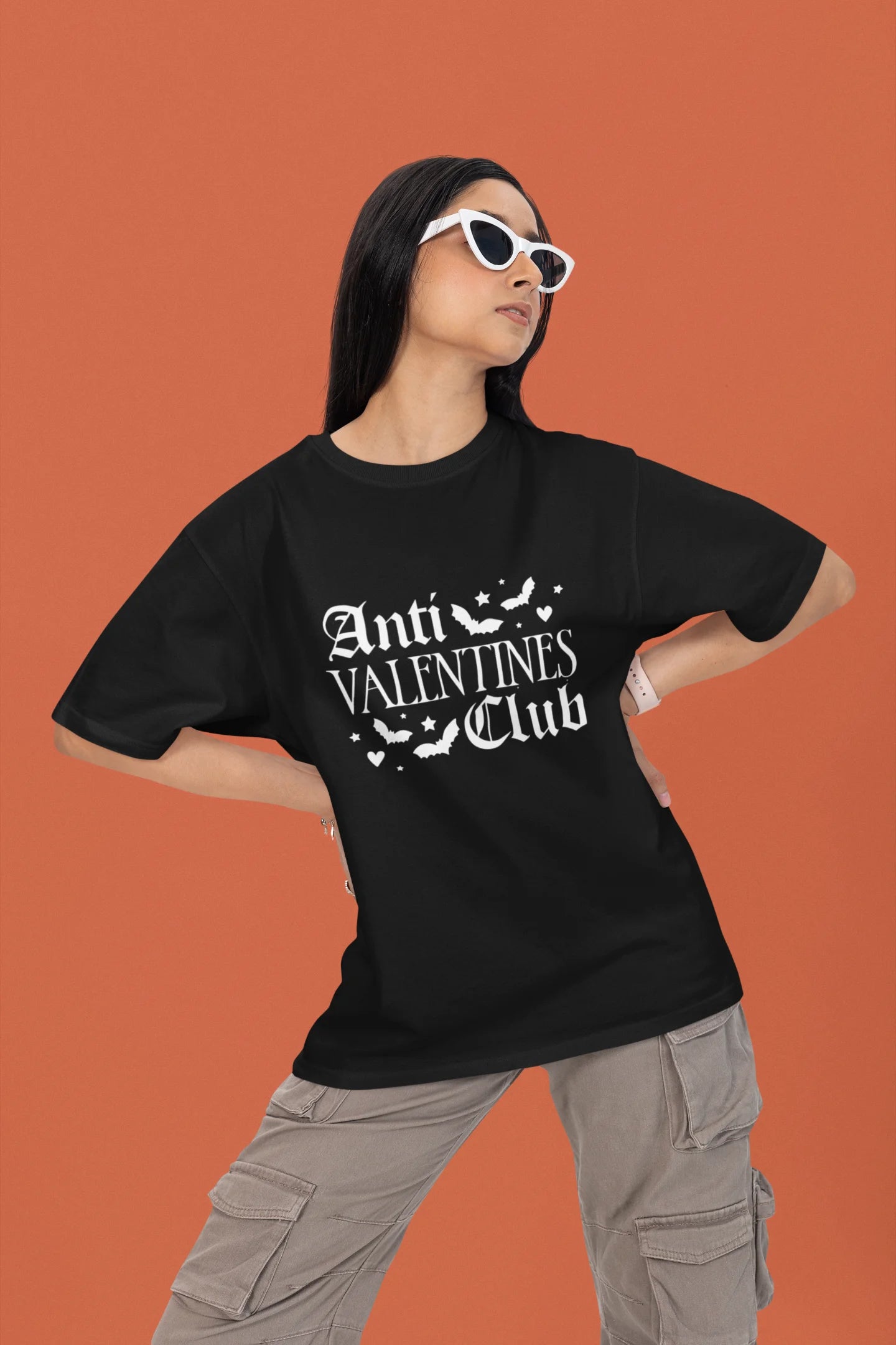 First front view of a female model wearing a black oversized t-shirt with the text "Anti-Valentine's Club" printed on it.