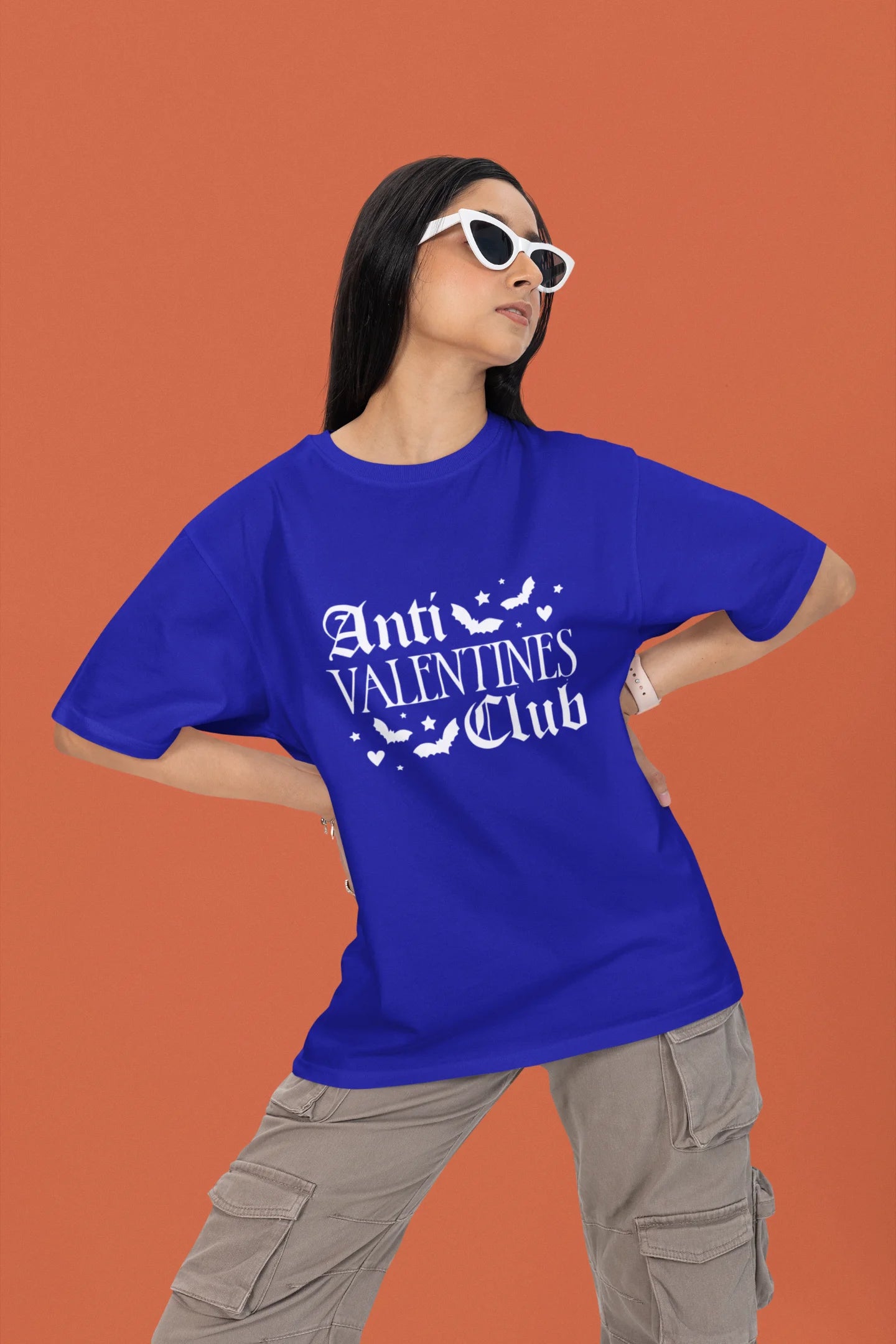 First front view of a female model wearing a royal blue oversized t-shirt with the text "Anti-Valentine's Club" printed on it.