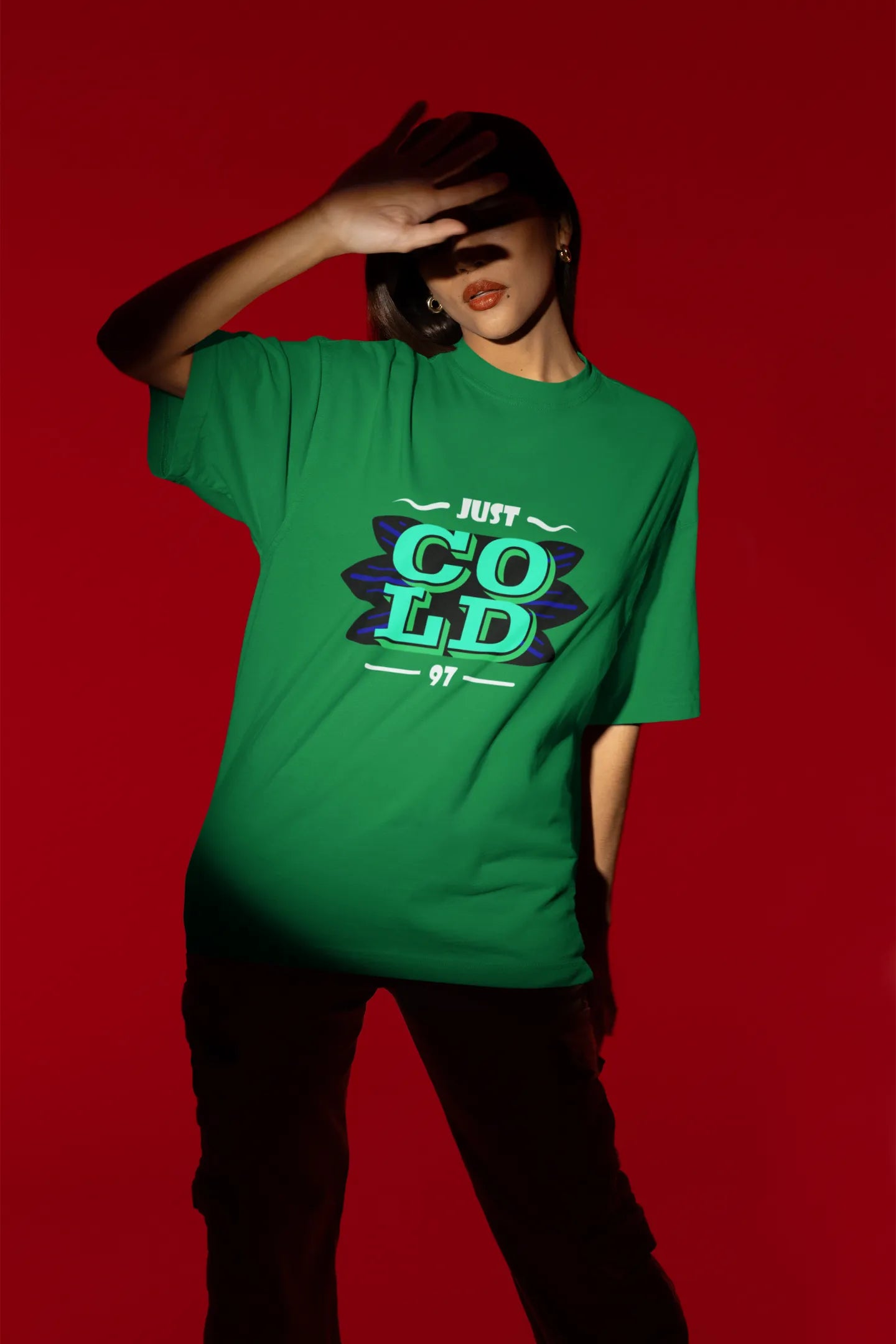 Fourth front view of a female model wearing an forest green oversized t-shirt with the text "Just Cold" printed on it.