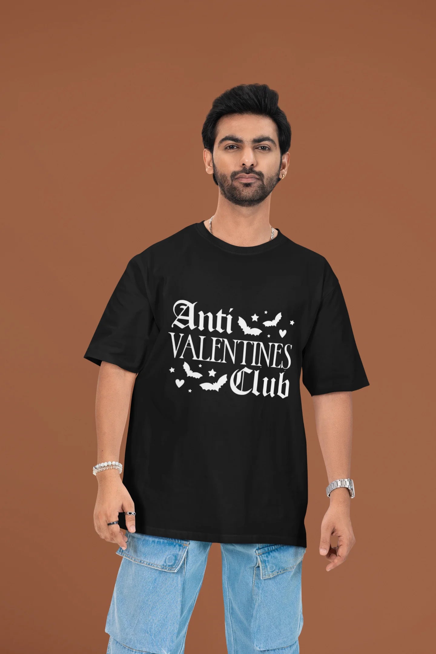 3rd view of a male model wearing a black oversized t-shirt with the text "Anti-Valentine's Club" printed on it.