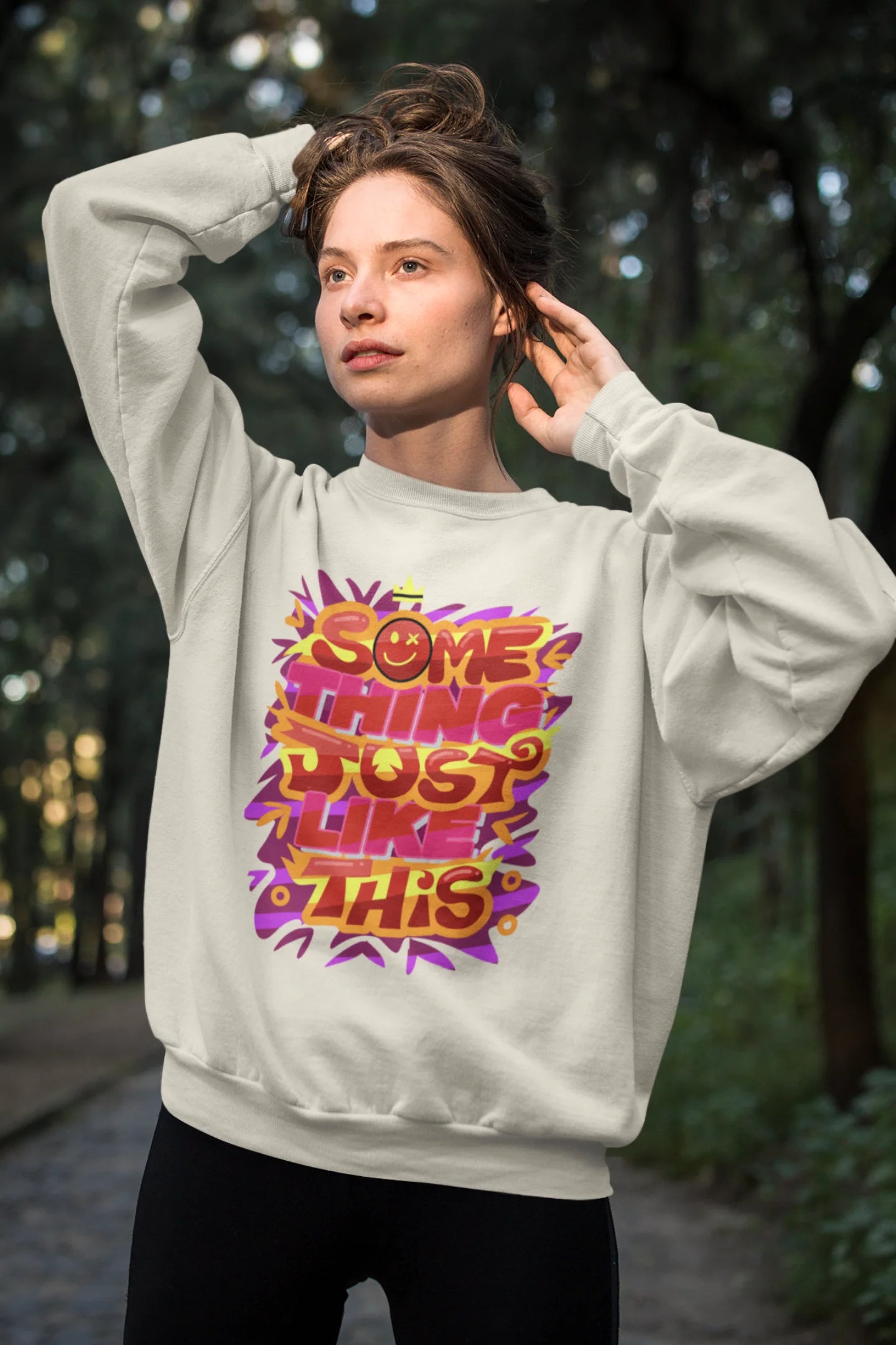 Third front view of a female model wearing an cream sweatshirt featuring the designs inspired from Coldplay's "Something Just Like This" music video.