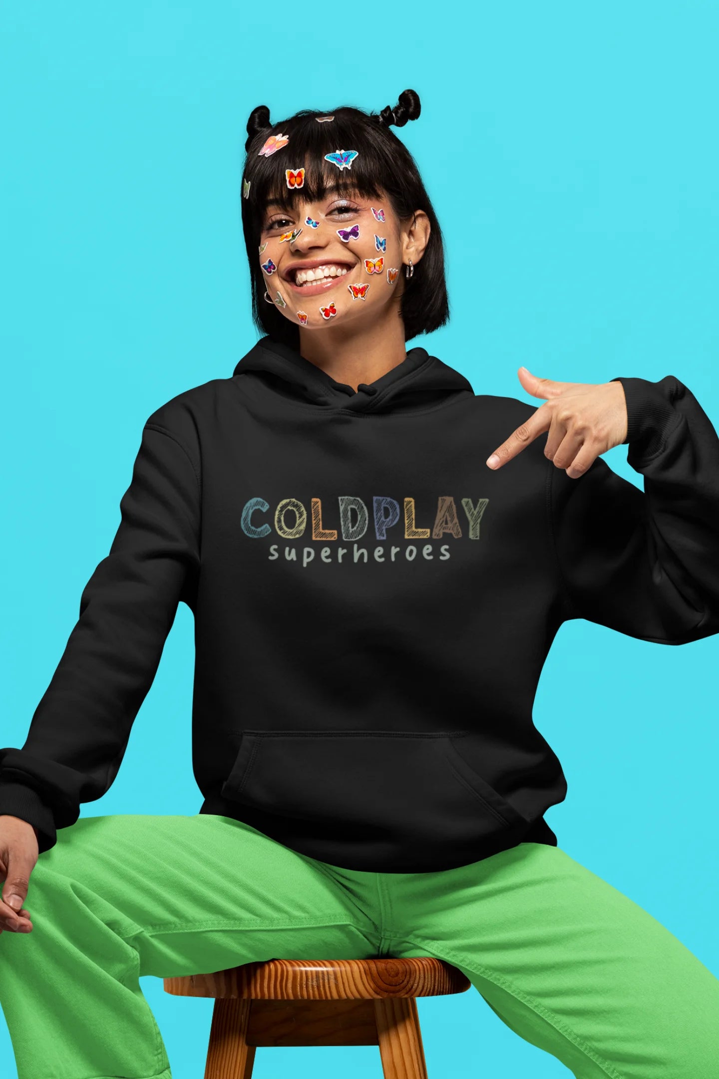 6th front view of a female model wearing an black hoodie with a design inspired by the "Something Just Like This" music video, featuring the word "Superheroes".