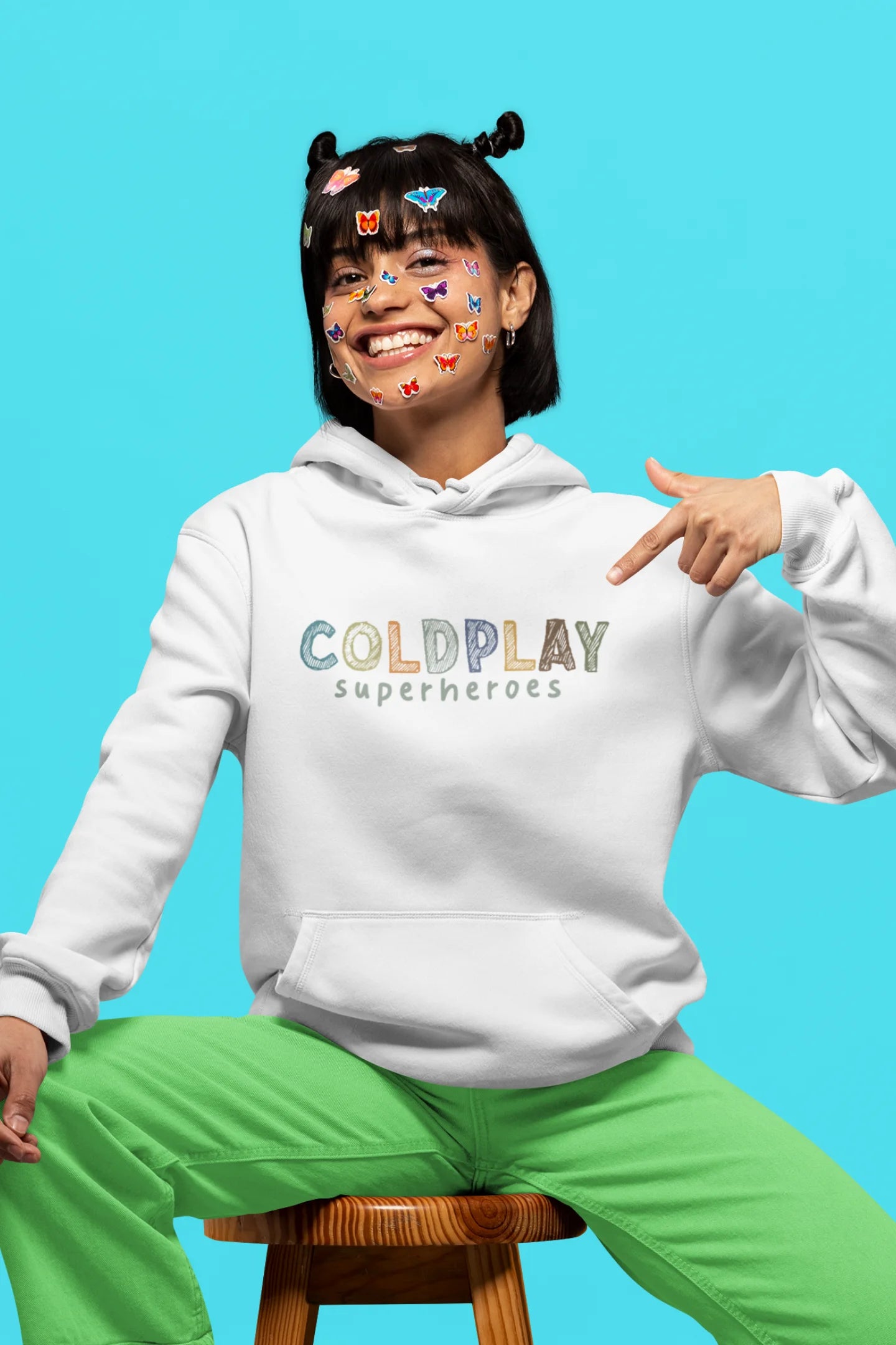2nd front view of a female model wearing an off-white hoodie with a design inspired by the "Something Just Like This" music video, featuring the word "Superheroes".